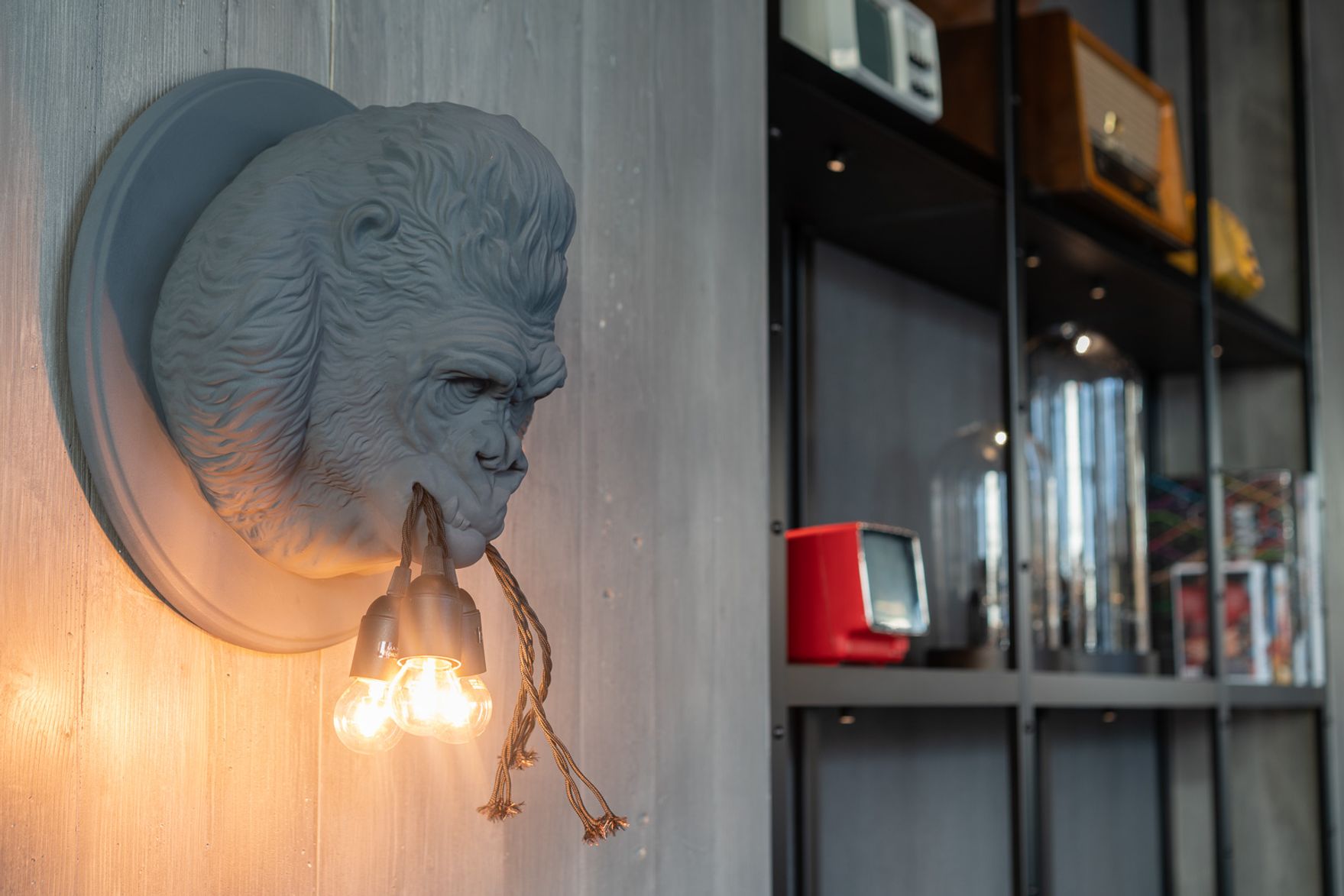 Designhotel Berlin Spittelmarkt Motel One Nahaufnahme auf eine Affenskulptur an der Wand, der Glühbirnen festhält
