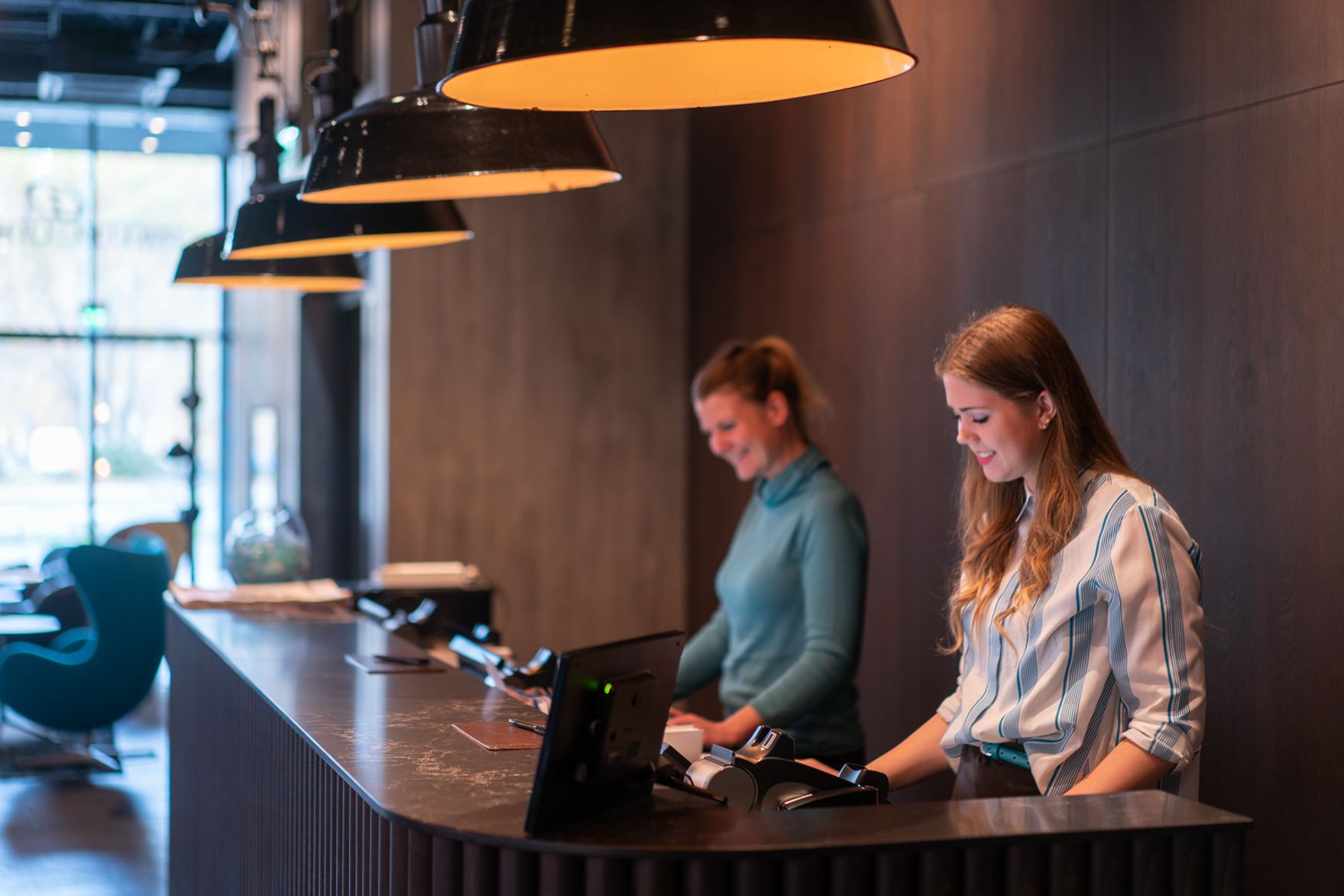 Designhotel Berlin Spittelmarkt Motel One Rezeption mit zwei Mitarbeiterinnen bei der Arbeit