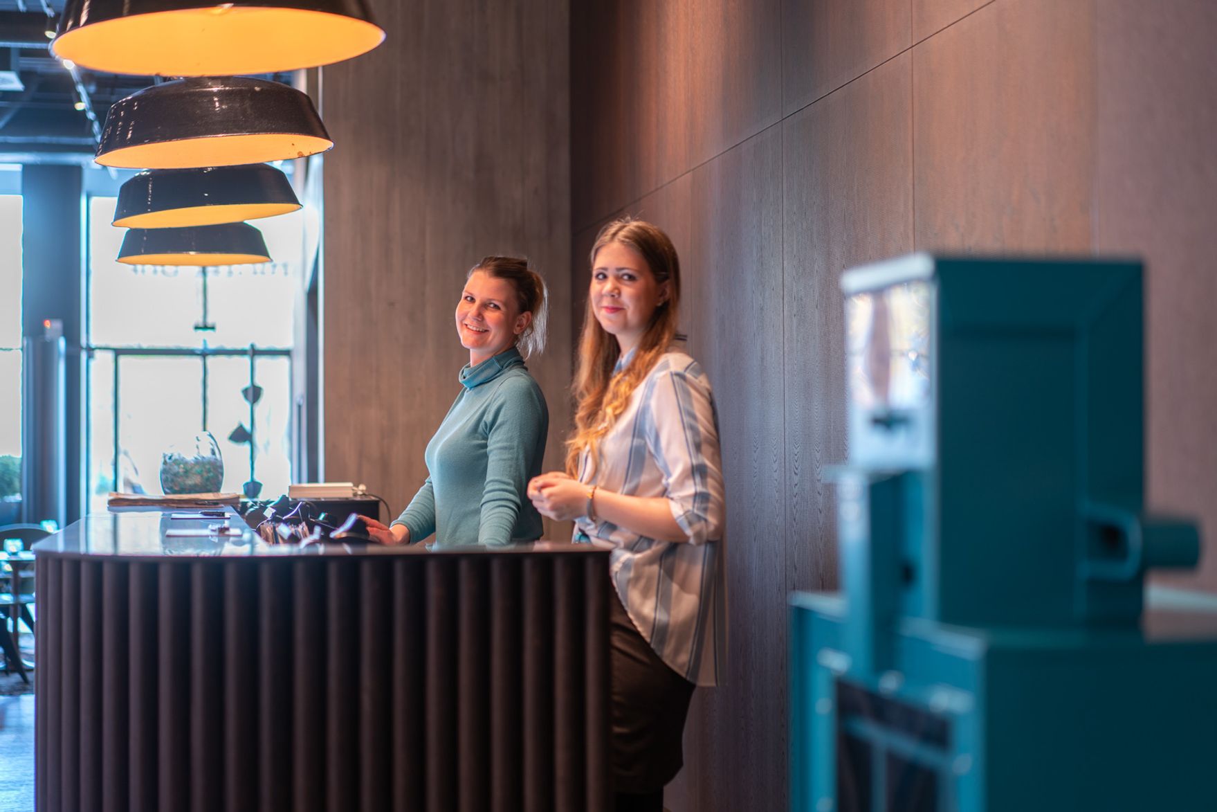 Hotel Berlin Spittelmarkt Motel One Rezeption mit zwei Mitarbeiterinnen, die in die Kamera lächeln