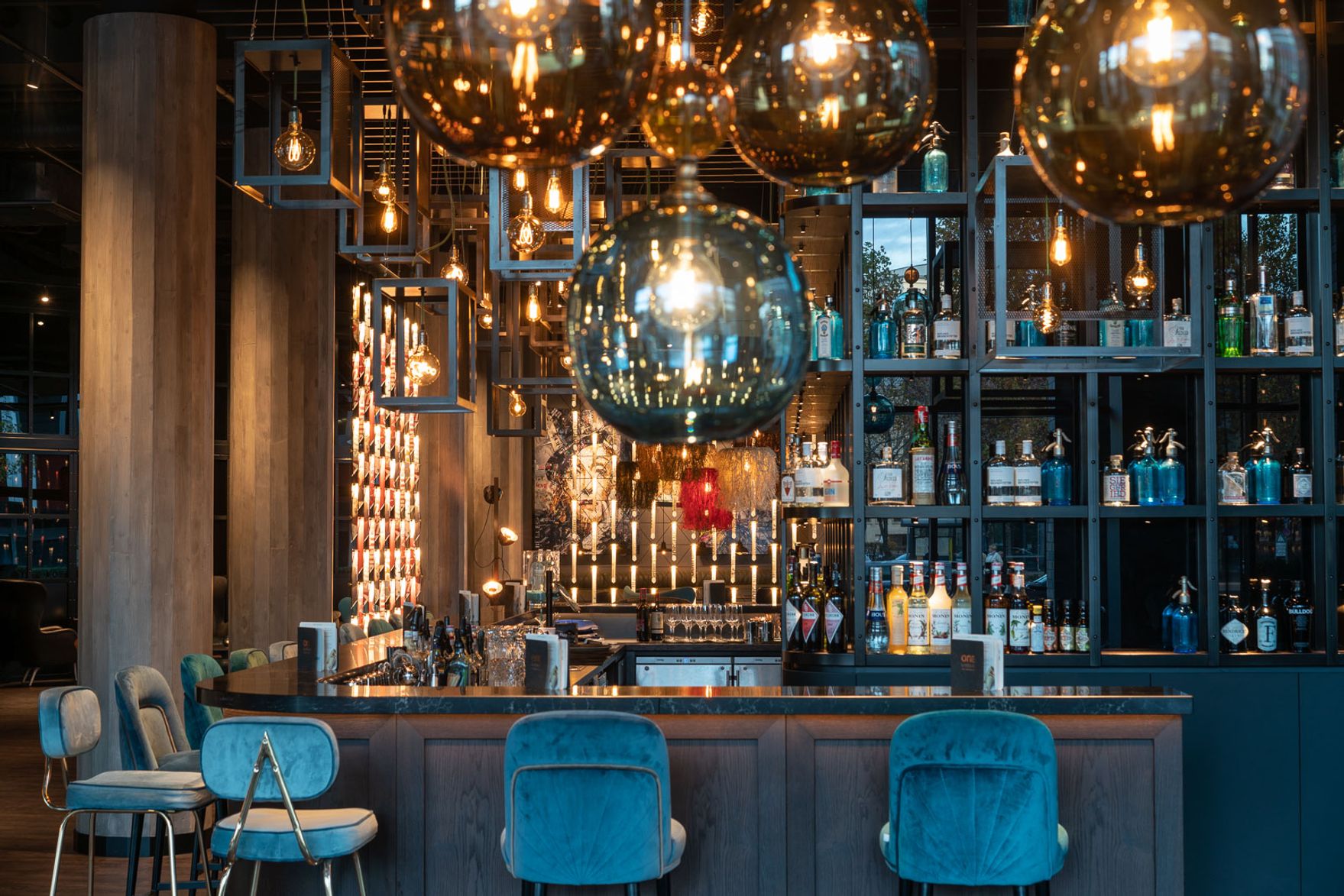 Designhotel Berlin Spittelmarkt Motel One Blick auf große Bar mit mehreren Barhockern und Spirituosen in den Regalen