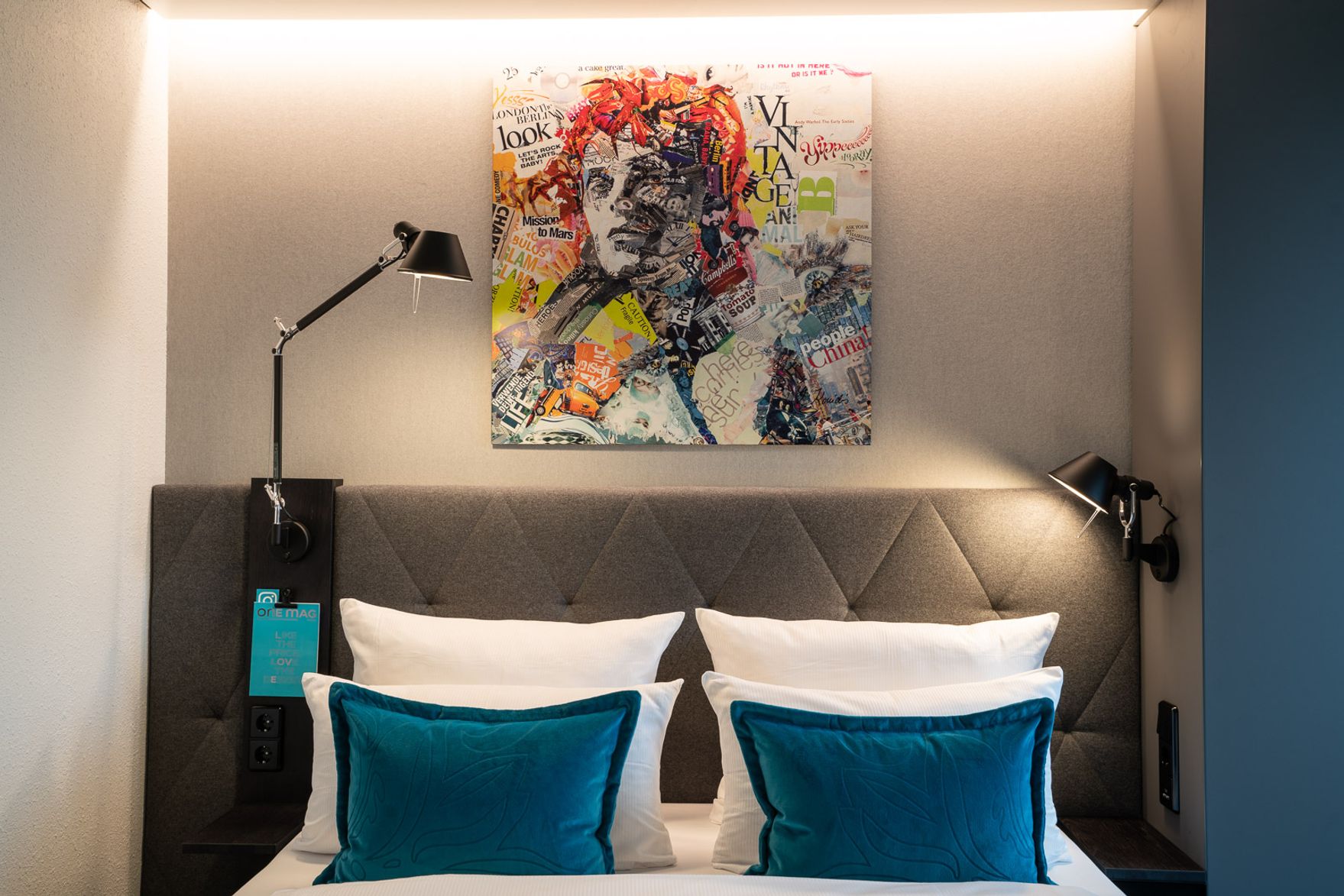 Hotel Berlin Spittelmarkt Motel One Zimmer mit Blick auf ein Doppelbett mit zwei Zierkissen in türkis sowie ein modernes Gemälde über dem Bett