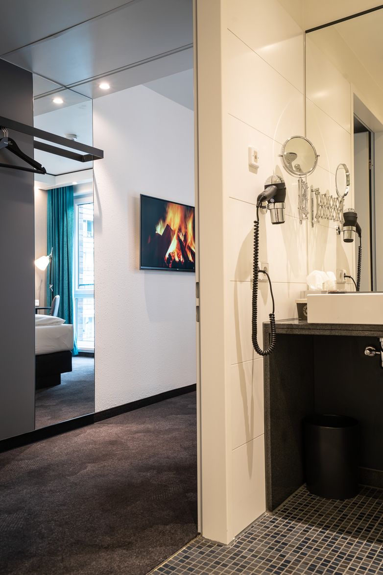 Hotel Berlin Spittelmarkt Motel One Zimmer mit Blick vom Bad in den Flur hinein mit großem Spiegel und Fernseher an der Wand