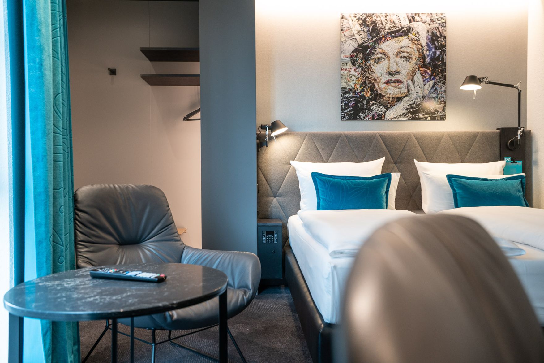 Hotel Berlin Spittelmarkt Motel One lichtdurchflutetes Zimmer mit Blick auf ein Doppelbett sowie einen Stuhl und Tisch