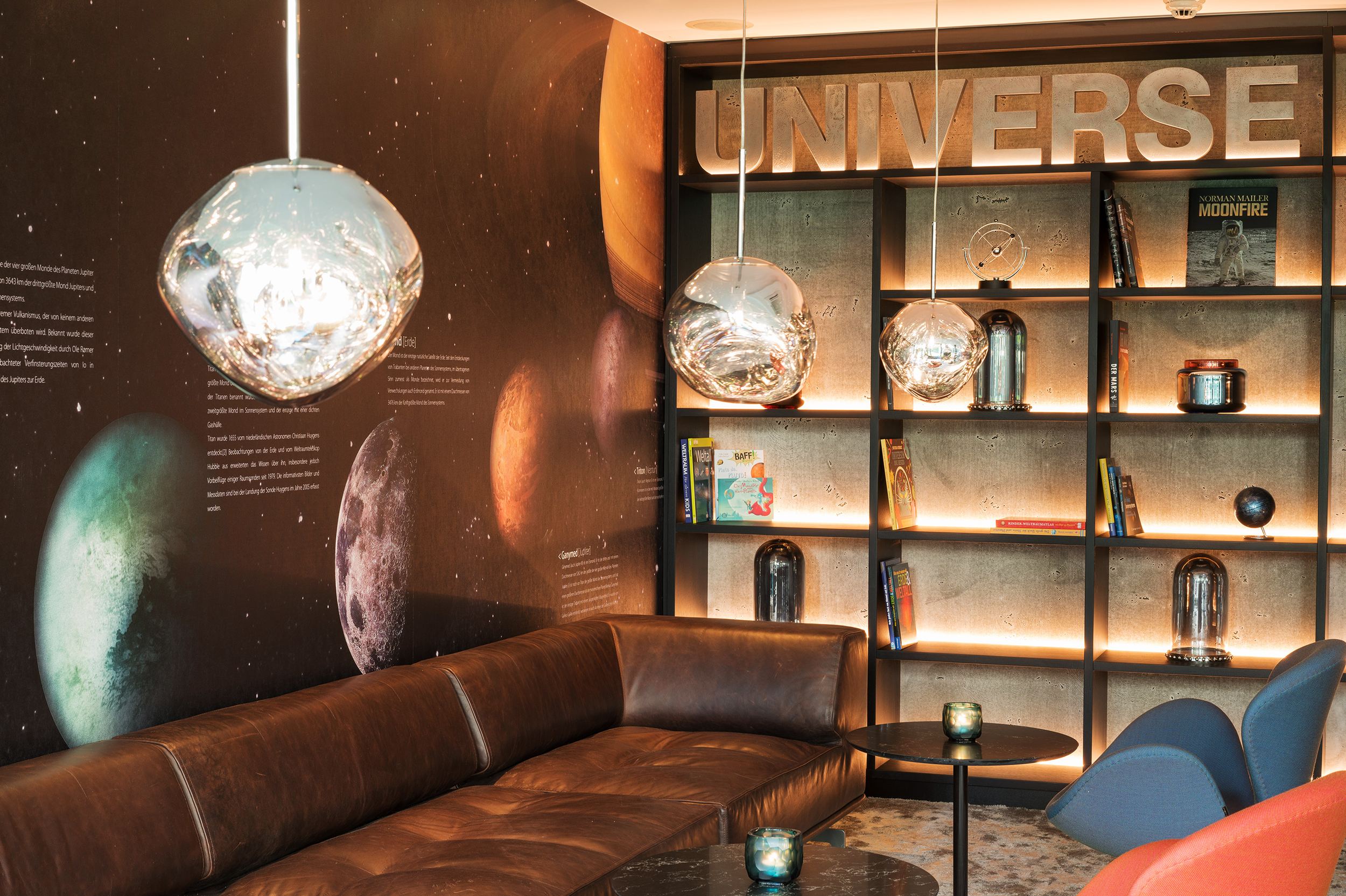 hotel Berlin Tiergarten Motel One lounge with large couch and armchairs, as well as an open shelf with decorations in a space-themed design