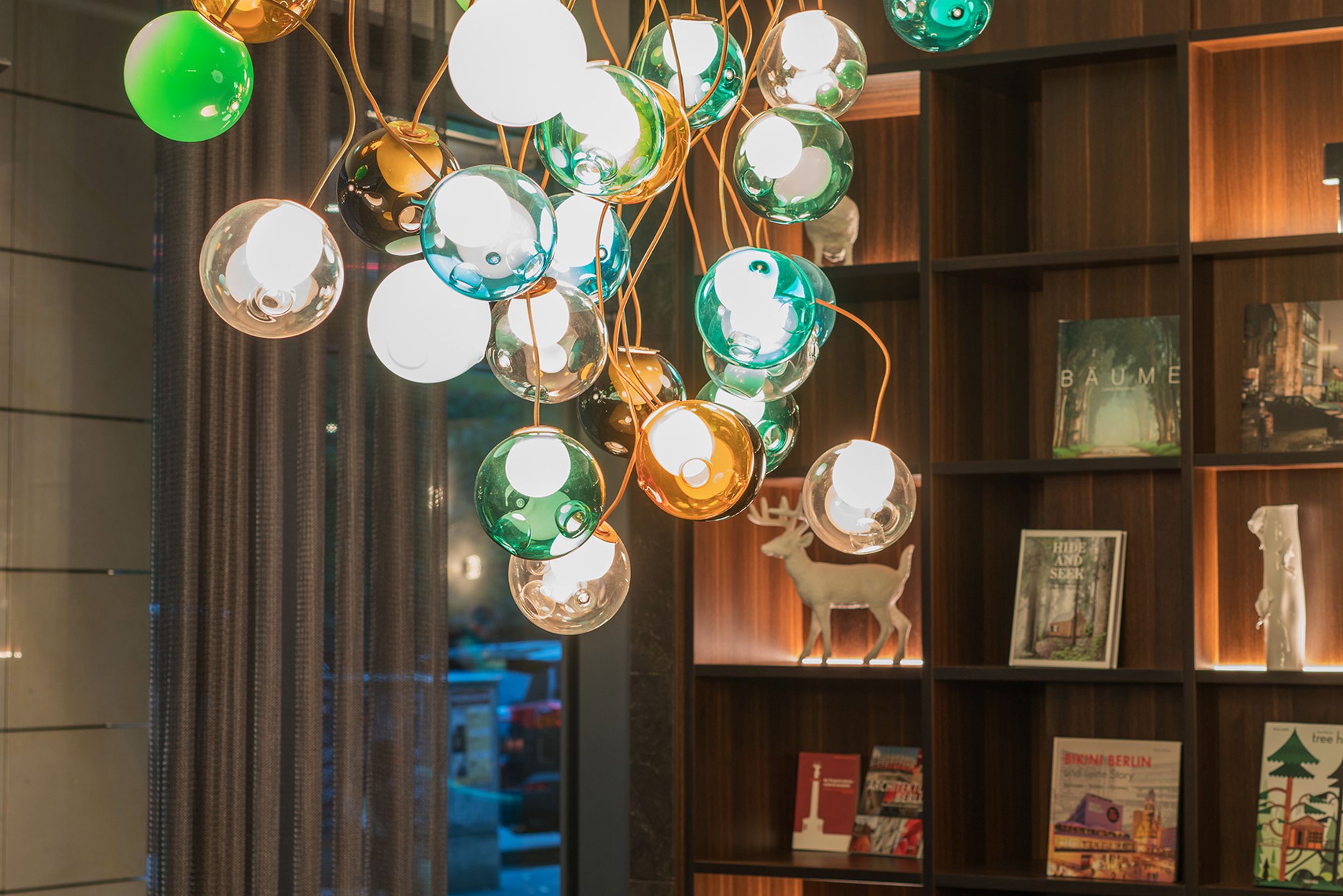 hotel Berlin Tiergarten Motel One room with a long table and several chairs, as well as a designer lamp with round, colorful glass shades