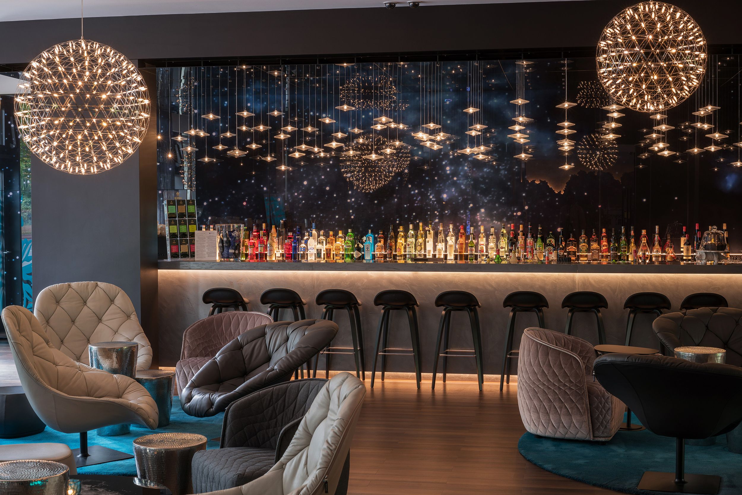 Designhotel Berlin Tiergarten Motel One Lounge mit Sesseln und Tischen zum Verweilen sowie große Bar mit mehreren Barhockern