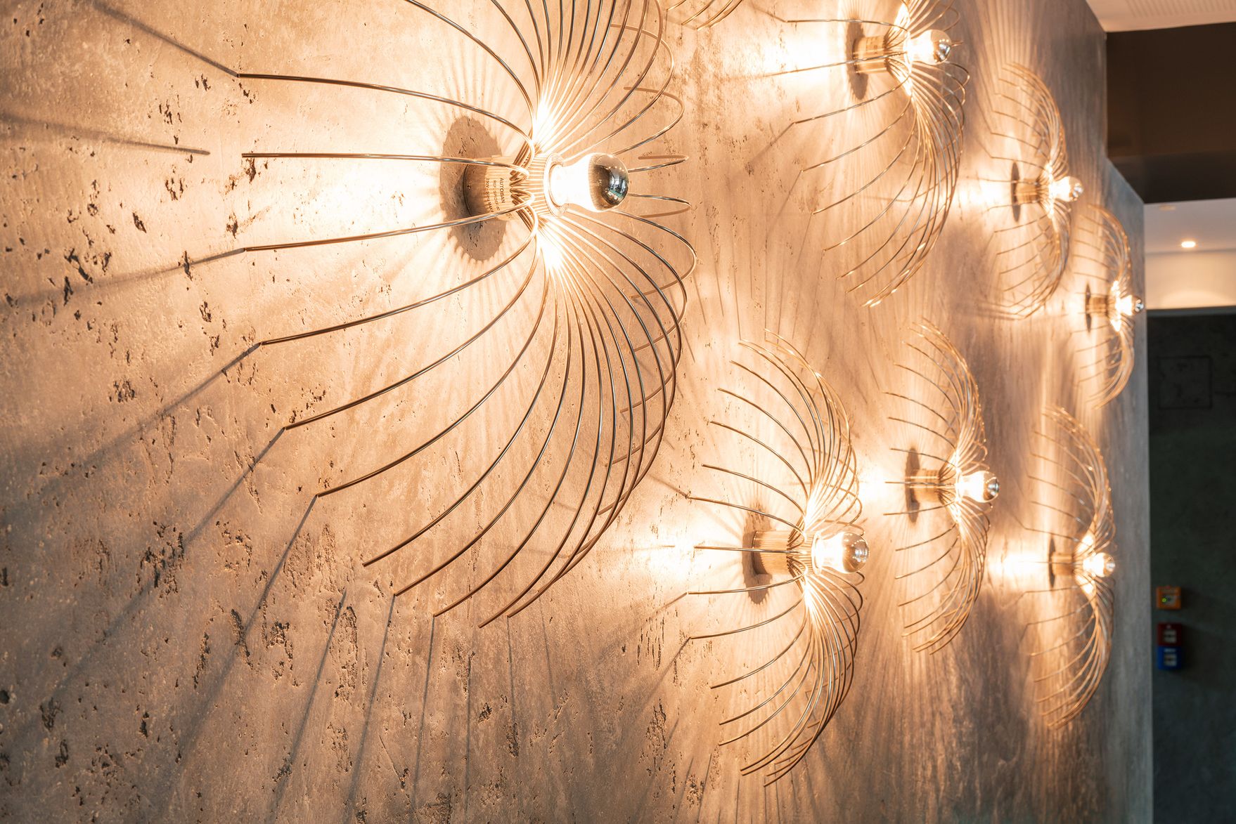 Hotel Berlin Tiergarten Motel One Blick auf eine helle Wand mit mehreren leuchtenden Designerlampen