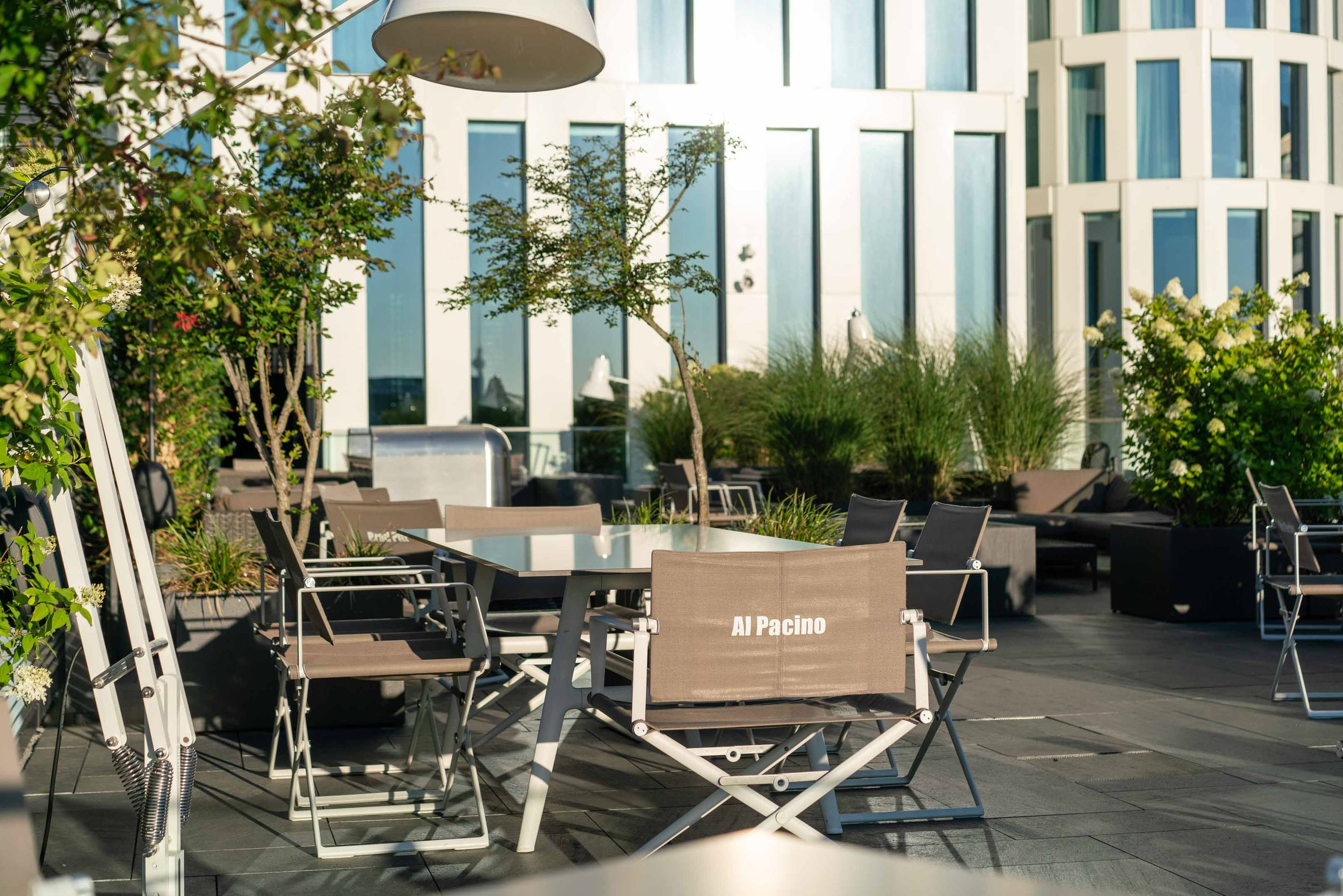 Designhotel Berlin Upper West Motel One sonnige Dachterrasse mit Blick auf mehrere Tische und Regiestühle