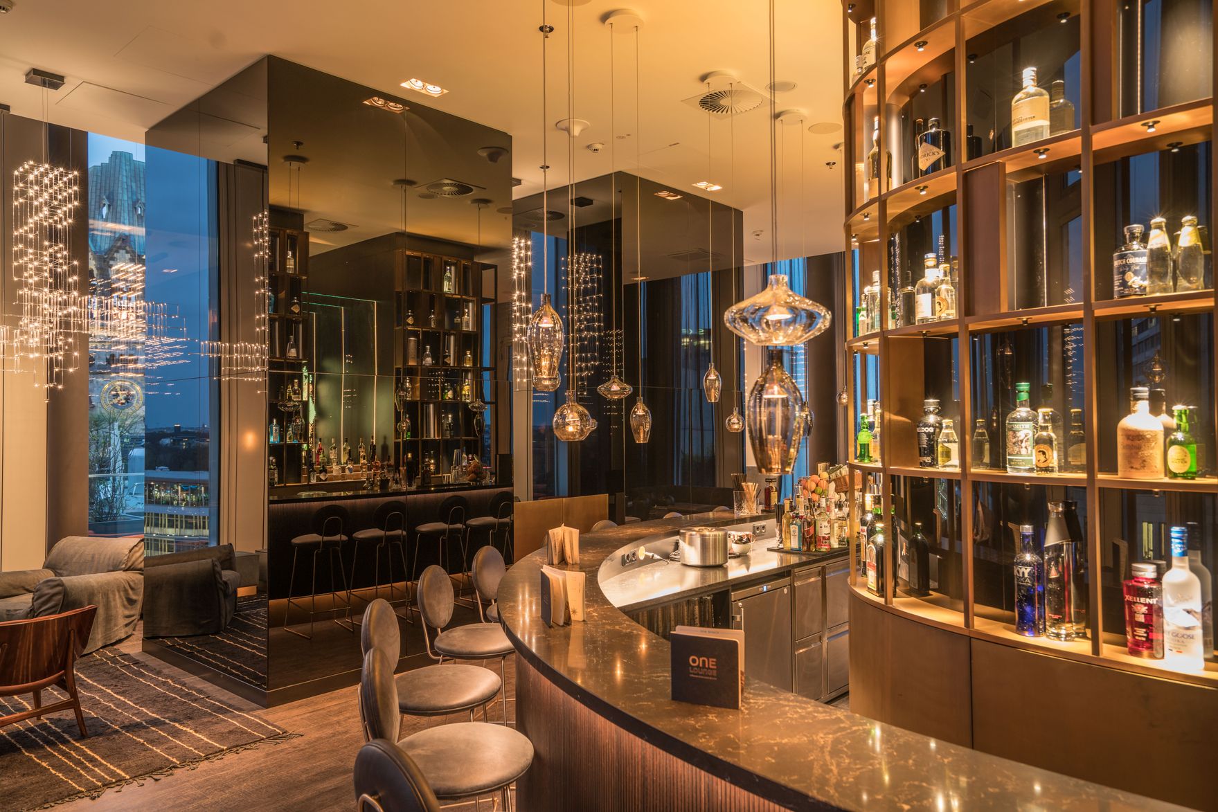 Hotel Berlin Upper West Motel One große Lounge mit Sitzgelegenheiten und runde Bar mit zwei verspiegelten hohen Säulen