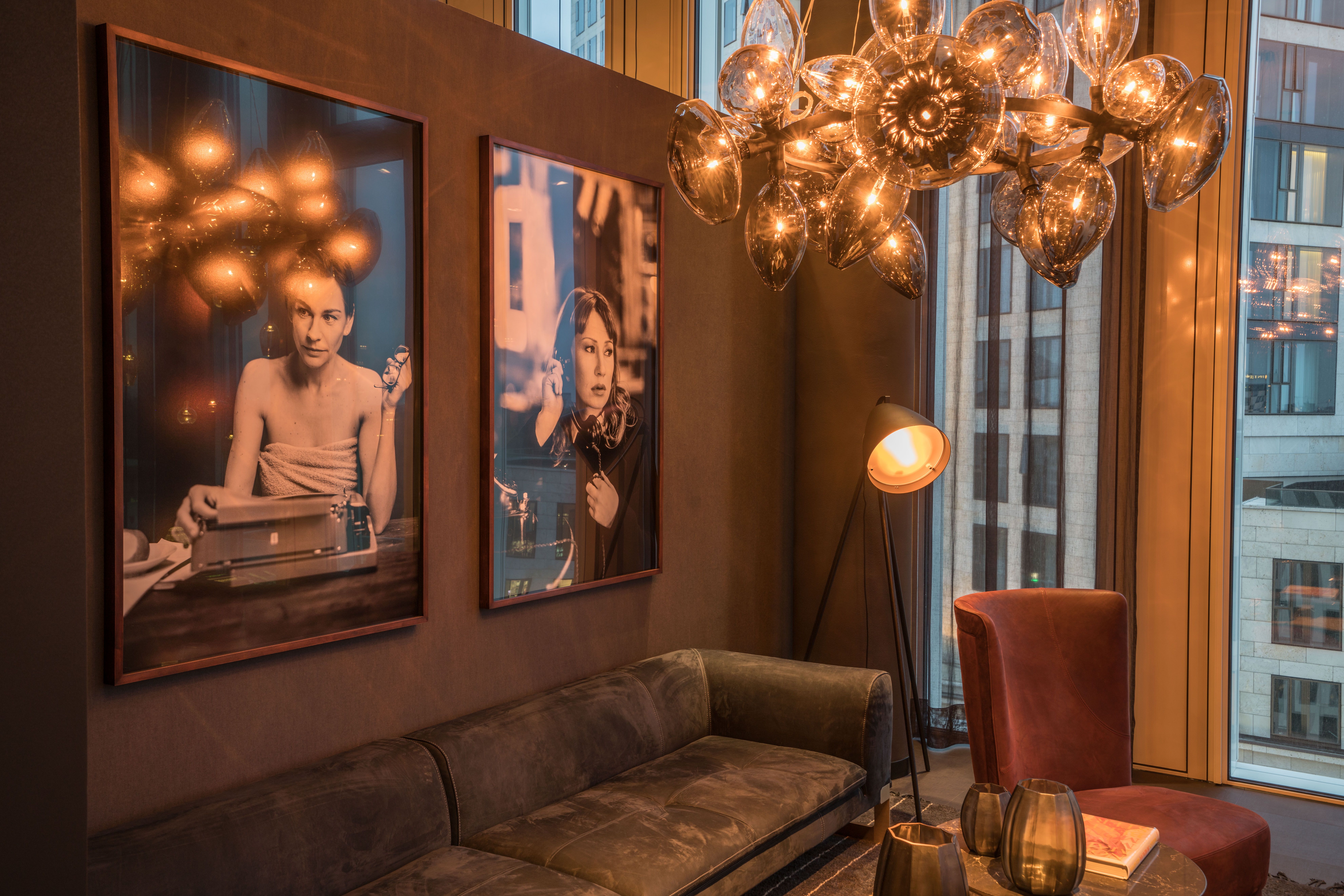 Designhotel Berlin Upper West Motel One Blick auf eine Sitzecke mit langer Couch und Sessel sowie zwei Bilder von Schauspielerinnen an der Wand