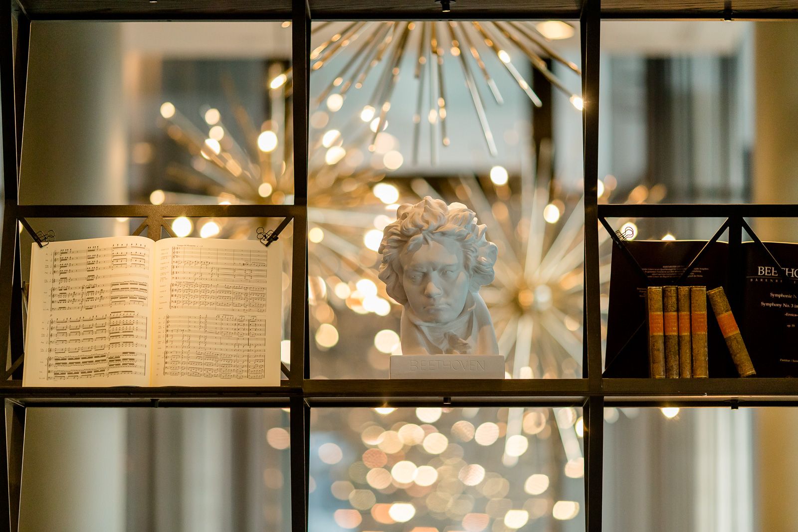 Hotel Bonn Beethoven Motel One Nahaufnahme offenes Dekorationsregal mit Noten, Beethoven Statue und Büchern