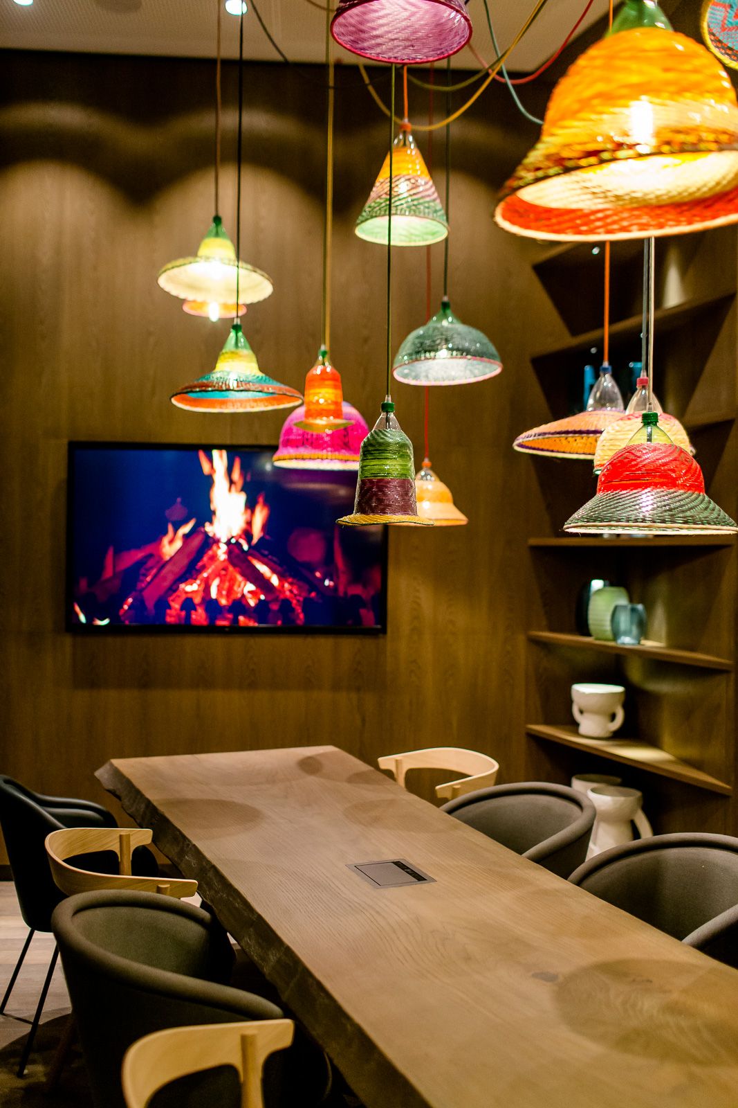 Hotel Bonn Hauptbahnhof Motel One Meetingraum mit Tisch und Fernseher an der Wand sowie bunten Deckenlampen