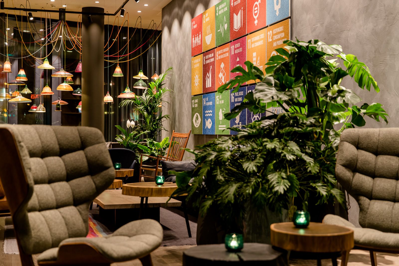 Designhotel Bonn Hauptbahnhof Motel One Lounge mit Sesseln, Beistelltischen und mehreren Pflanzen