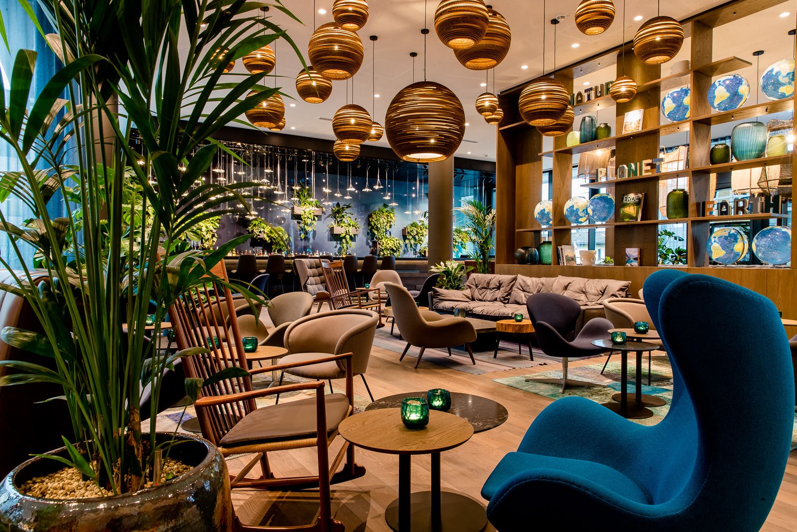 Designhotel Bonn Hauptbahnhof Motel One große und helle Lounge mit mehreren Sitzgelegenheiten sowie die Bar mit Pflanzenwand im Hintergrund