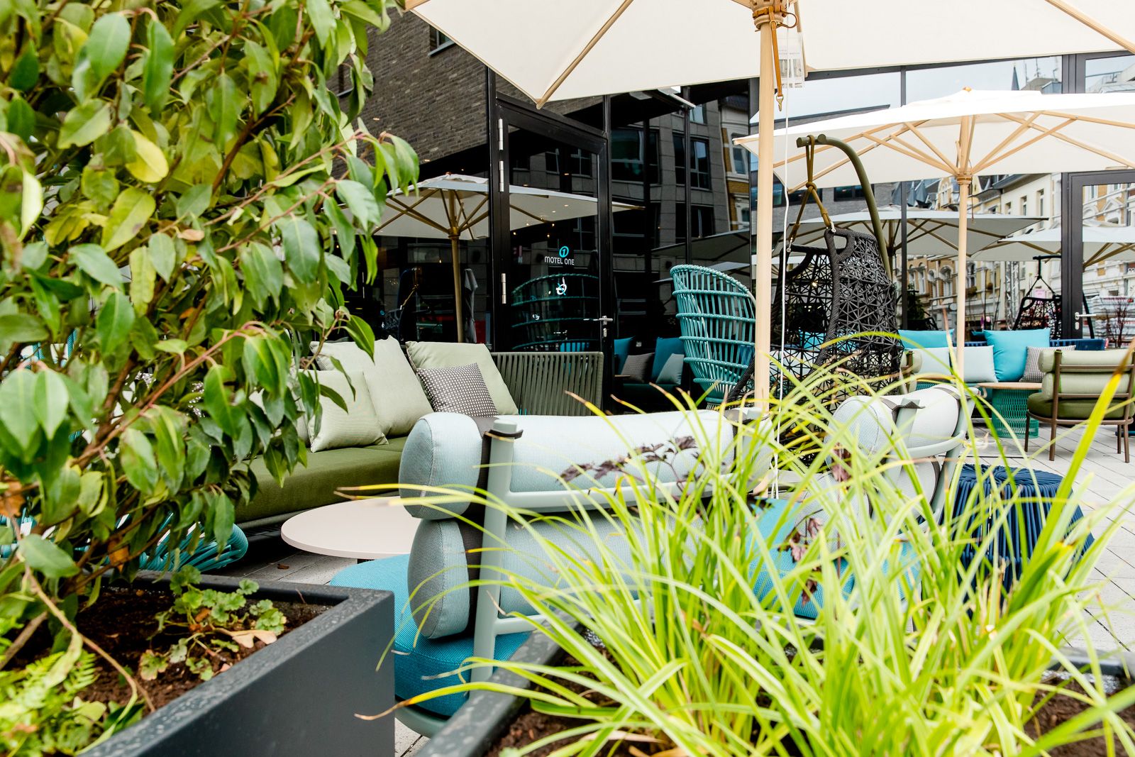 Designhotel Bonn Hauptbahnhof Motel One Terrasse mit mehreren Sitzgelegenheiten sowie Sonnenschirme