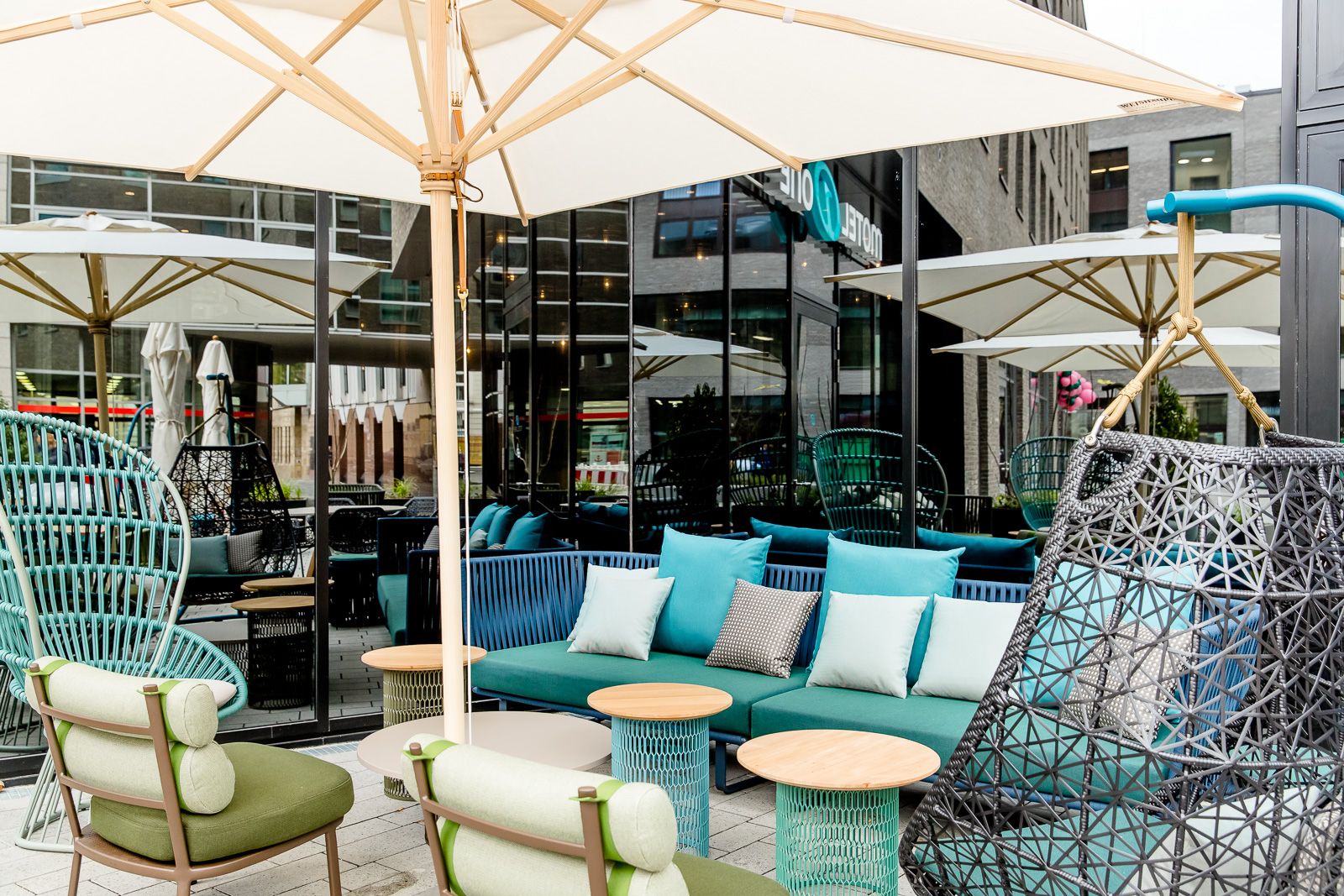 Designhotel Bonn Hauptbahnhof Motel One Außenbereich mit mehreren Sitzgelegenheiten sowie offene Sonnenschirme
