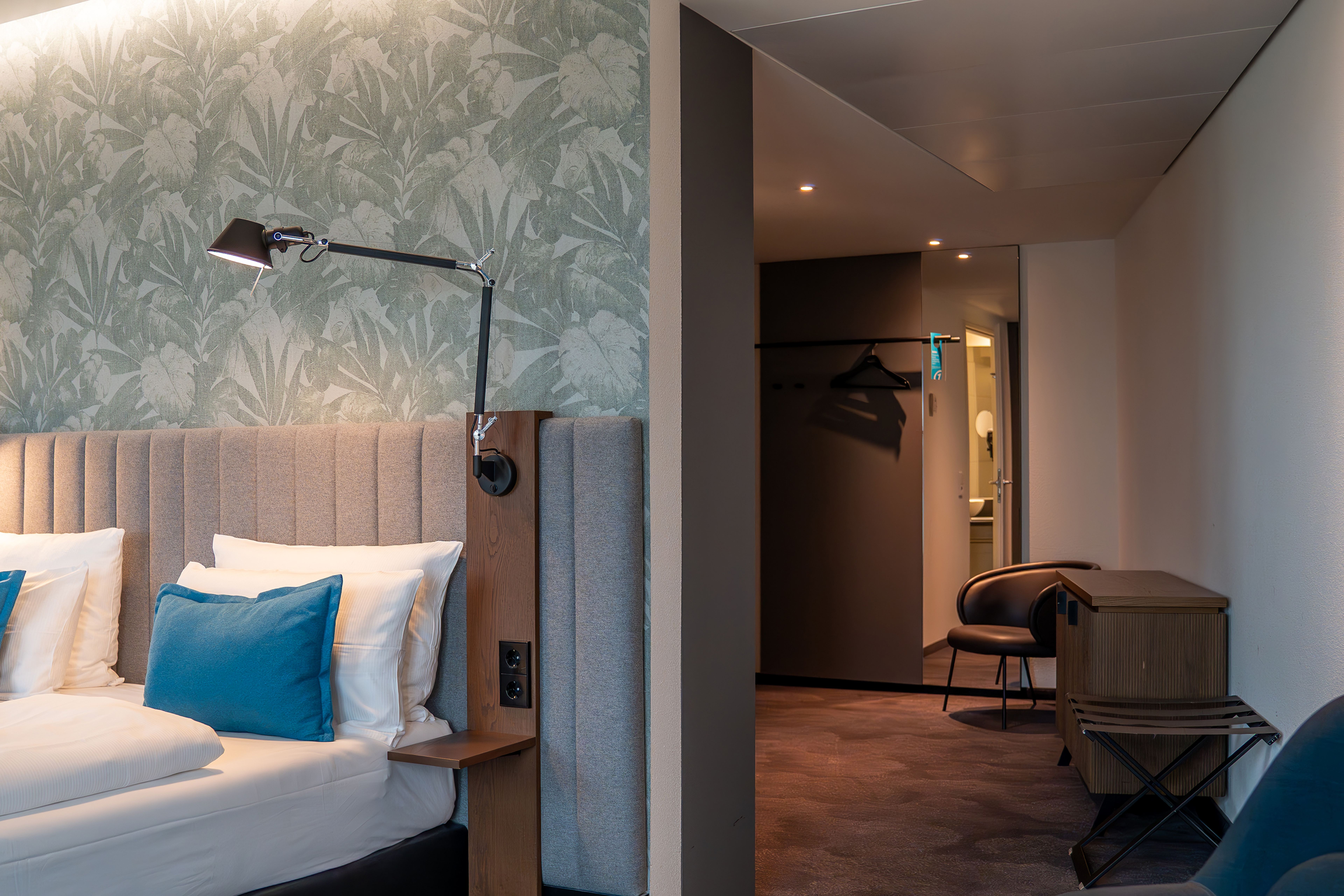 Hotel Bonn Hauptbahnhof Motel One großes Zimmer mit Blick auf ein Doppelbett sowie in einen großen Flur mit Kommode, Sessel und Garderobe Hotel Bonn Hauptbahnhof Motel One großes Zimmer mit Blick auf ein Doppelbett sowie in einen großen Flur mit Kommode, Sessel und Garderobe