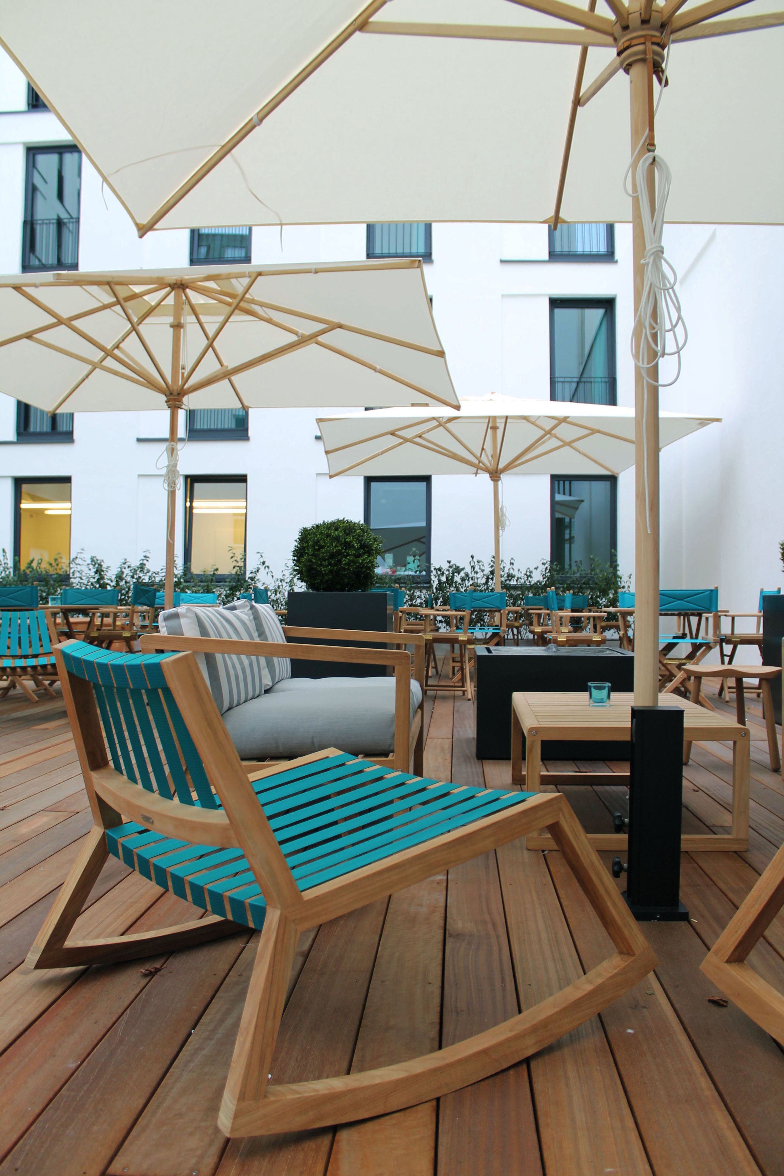 Designhotel Bremen Motel One große Terrasse mit mehreren Tischen und Stühlen sowie drei großen Sonnenschirmen