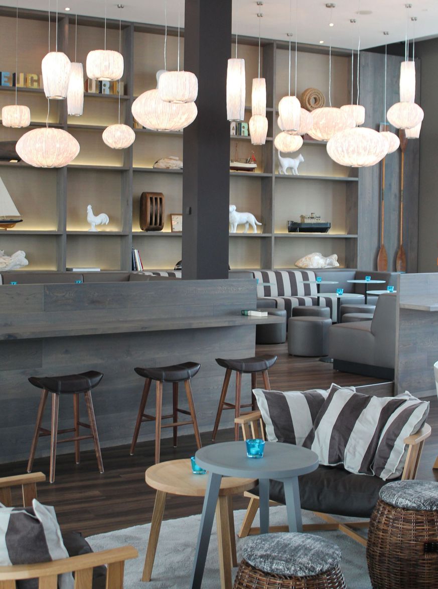 Hotel Bremen Motel One große und helle Lounge mit mehreren Sitzgelegenheiten sowie zahlreichen Deckenlampen