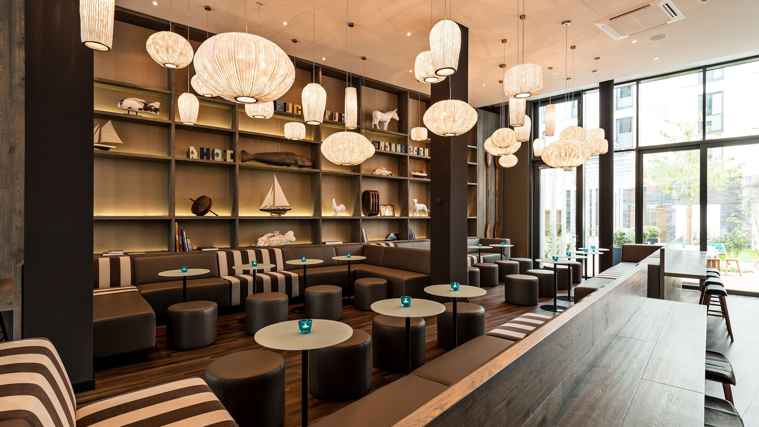 hotel Bremen Motel One large, bright lounge with plenty of seating, floor-to-ceiling windows, and a view of the terrace