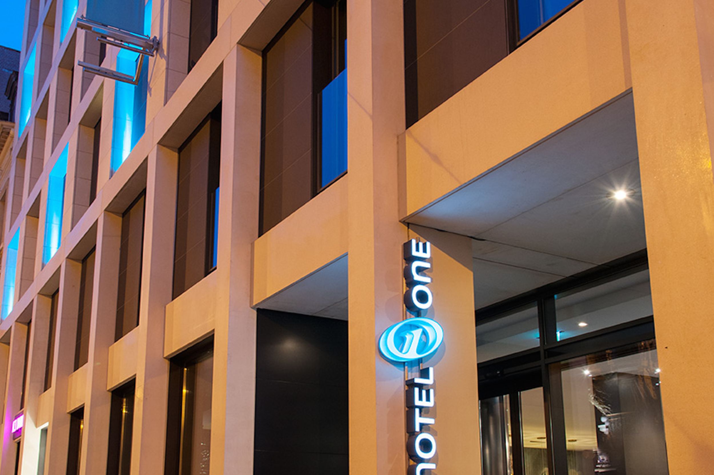 Designhotel Brüssel Motel One Fassade bei Abend mit Logo