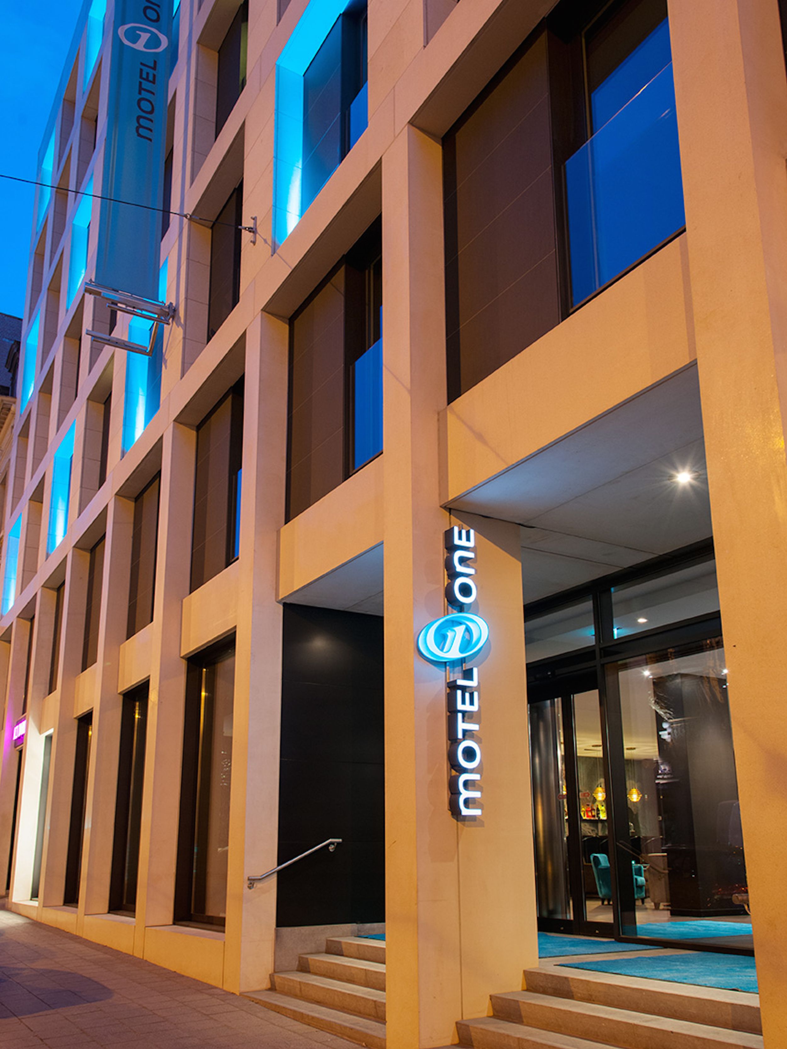 Designhotel Brüssel Motel One Fassade bei Abend mit Logo