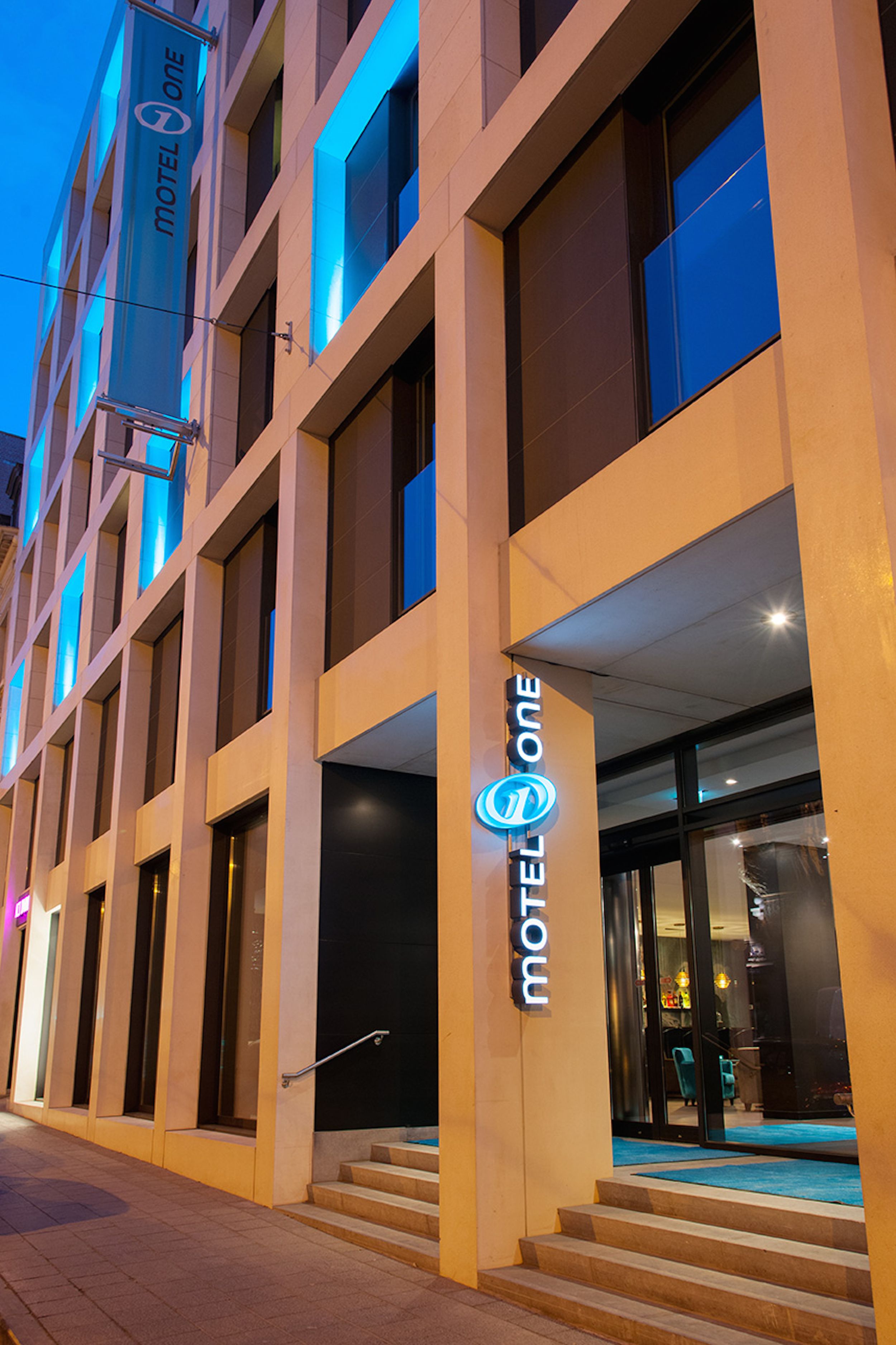 Designhotel Brüssel Motel One Fassade bei Abend mit Logo