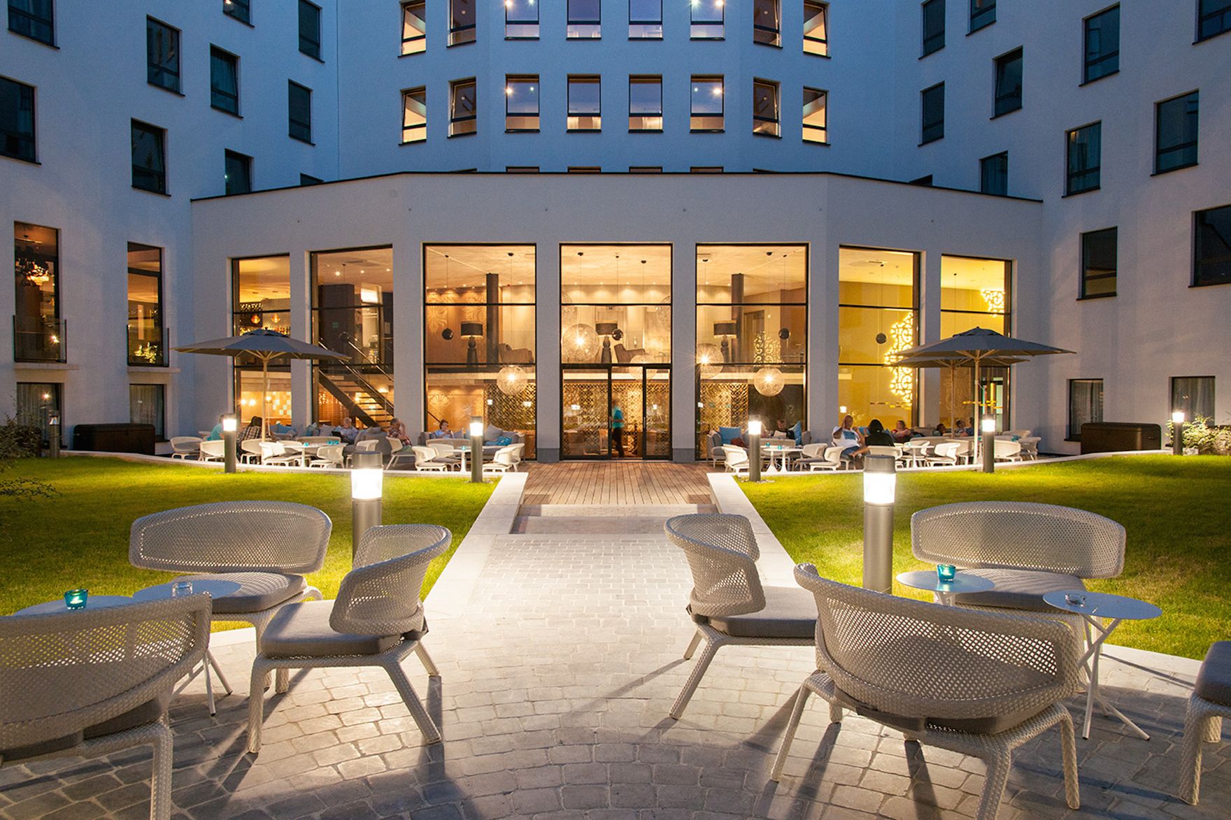 dsignhotel Brussels Motel One outdoor area in the evening with seating and a view of the building