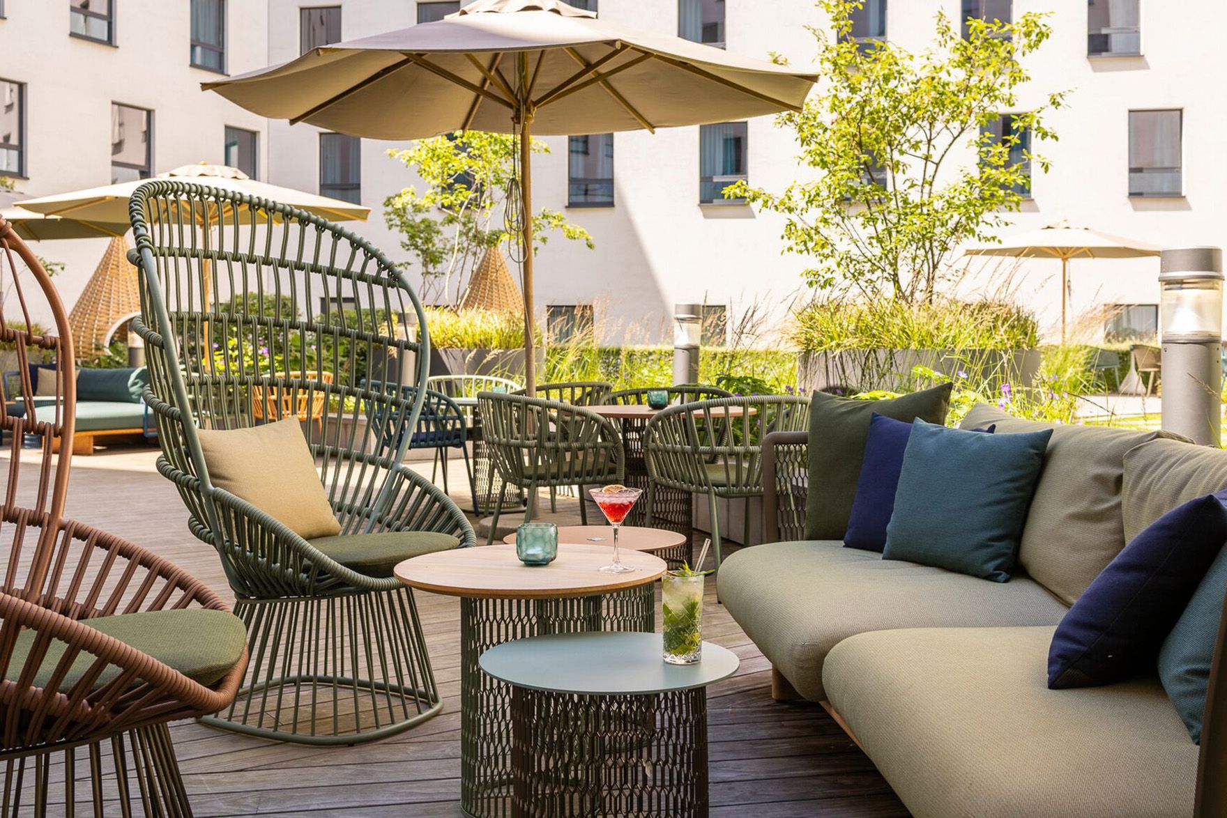 Hotel Brüssel Motel One sonnige Terrasse mit mehreren Sitzgelegenheiten sowie Sonnenschirm