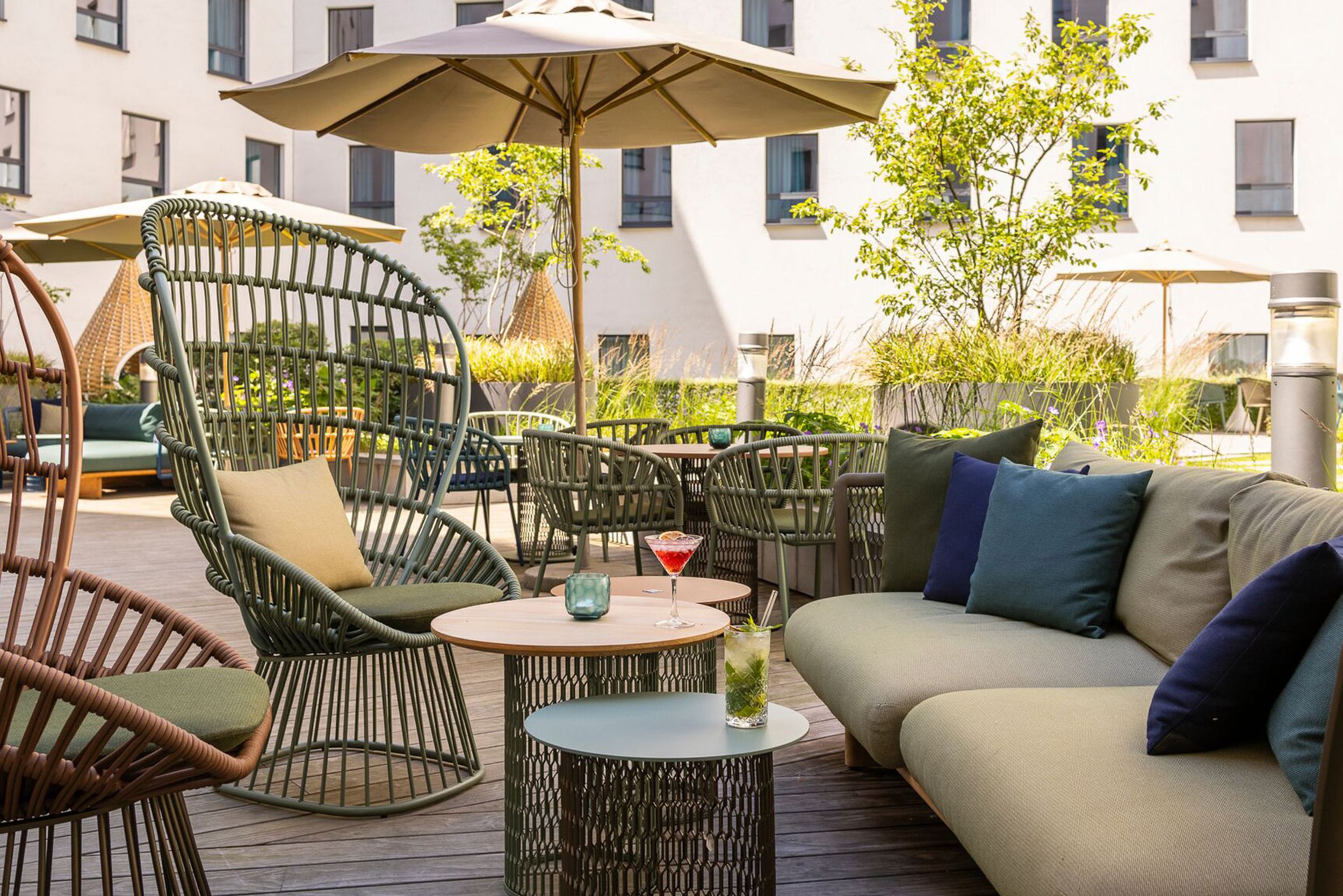 Hotel Brüssel Motel One sonnige Terrasse mit mehreren Sitzgelegenheiten sowie Sonnenschirm