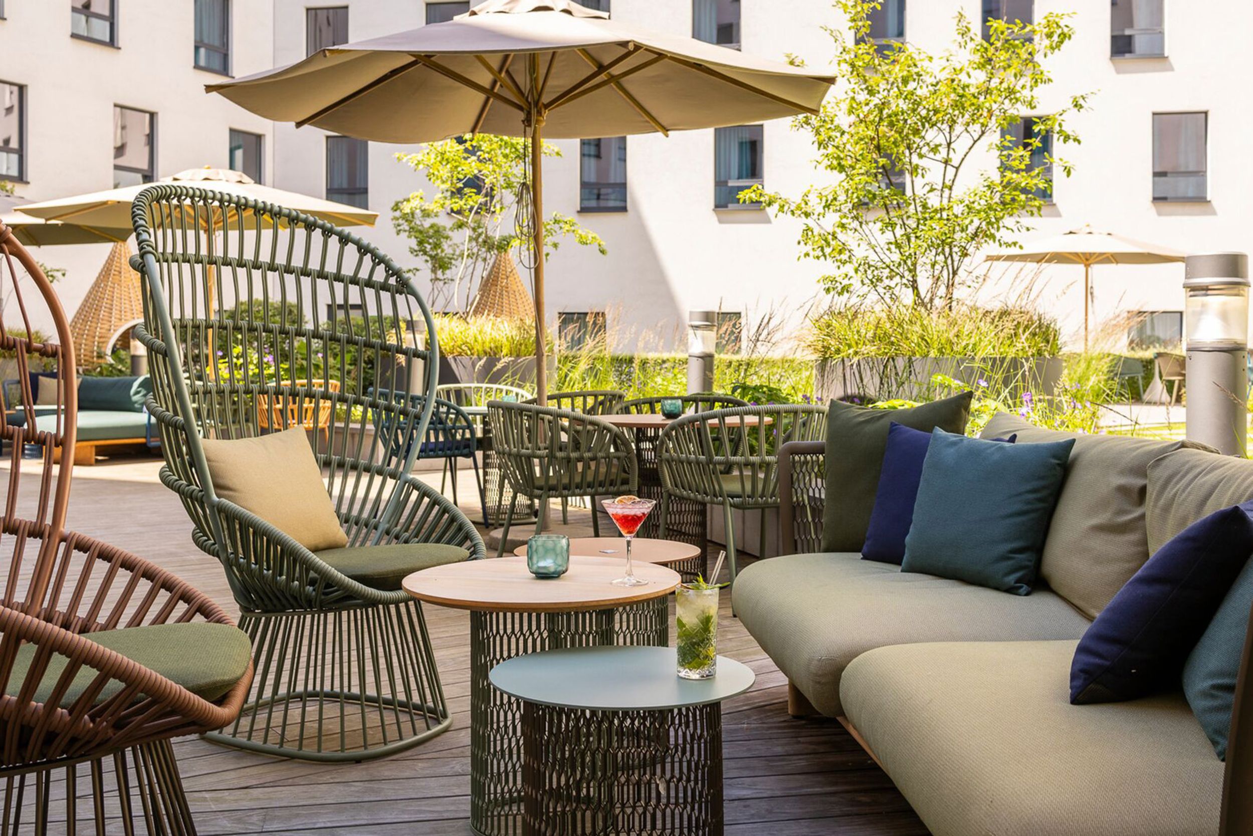Hotel Brüssel Motel One sonnige Terrasse mit mehreren Sitzgelegenheiten sowie Sonnenschirm