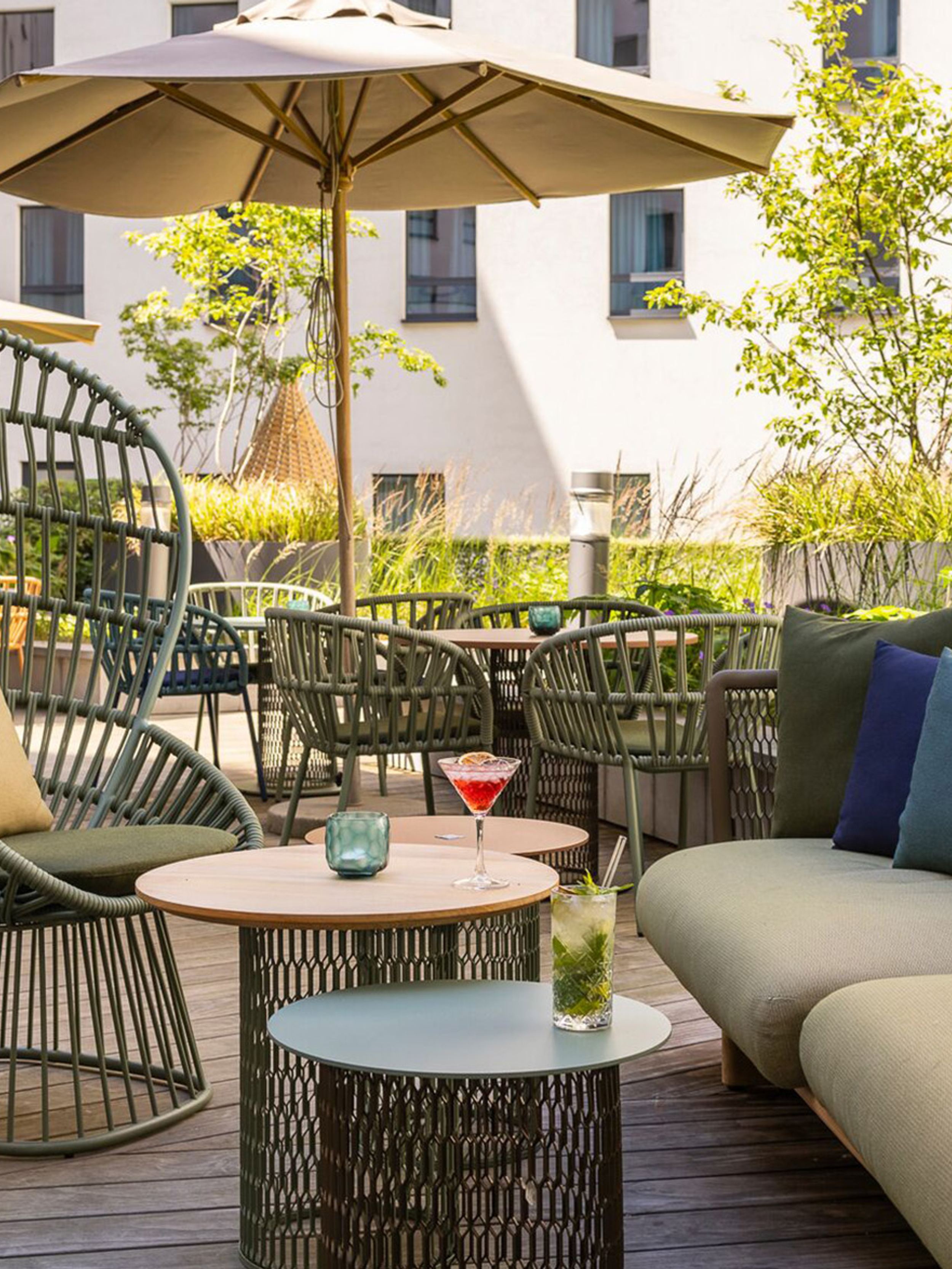 Hotel Brüssel Motel One sonnige Terrasse mit mehreren Sitzgelegenheiten sowie Sonnenschirm