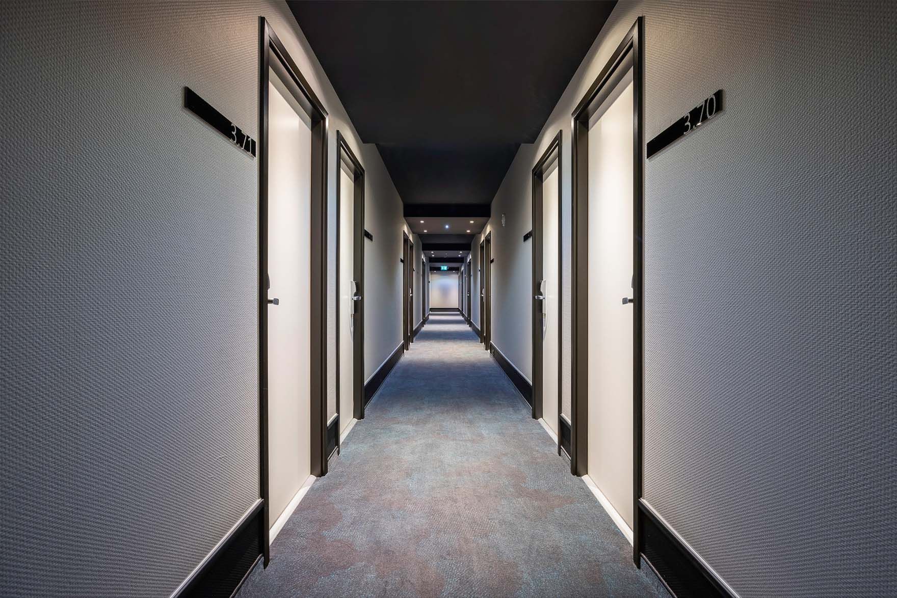 Designhotel Brüssel Motel One langer Hotelflur mit mehreren Türen, die zu den Zimmern abgehen