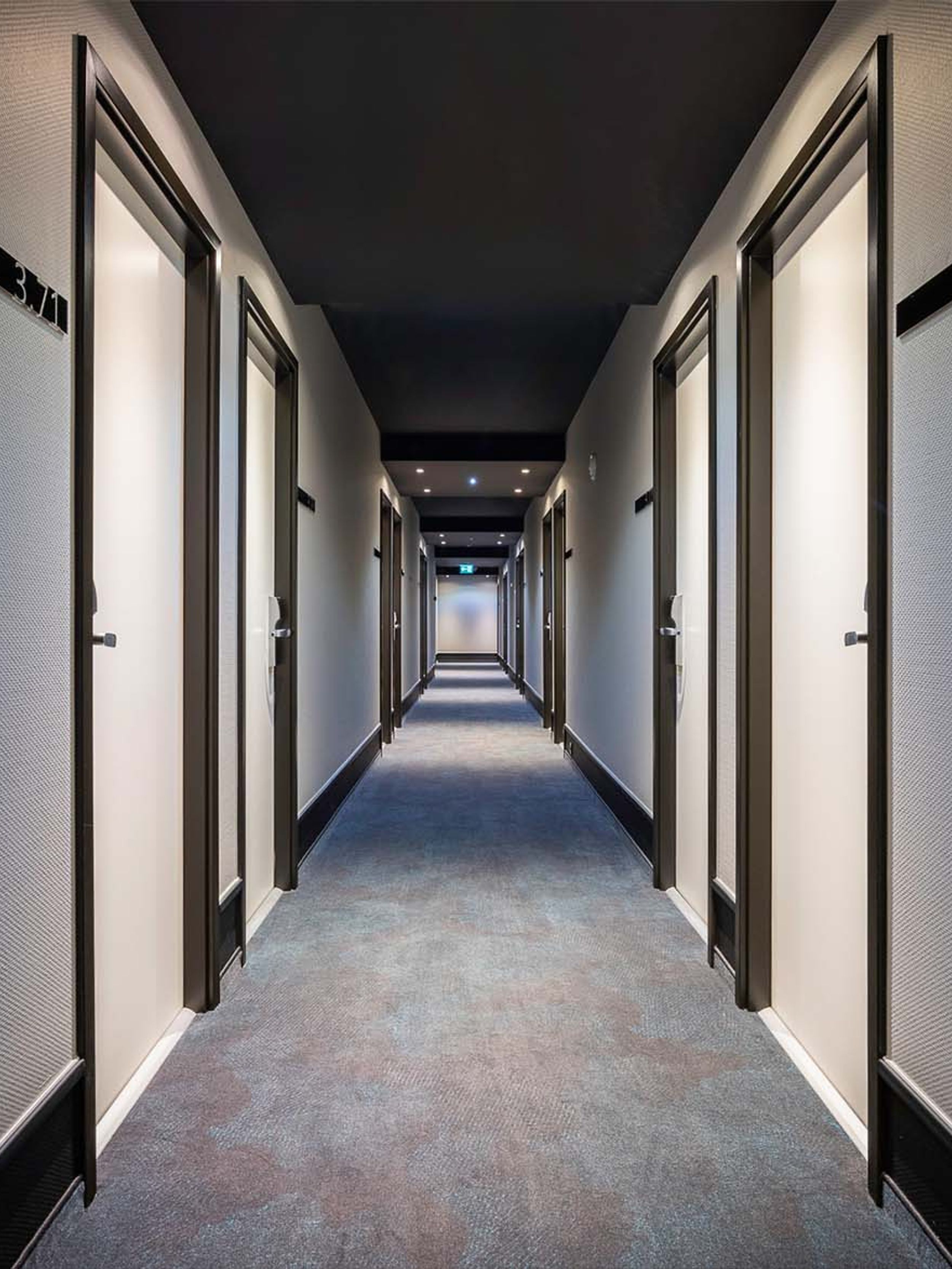 Designhotel Brüssel Motel One langer Hotelflur mit mehreren Türen, die zu den Zimmern abgehen
