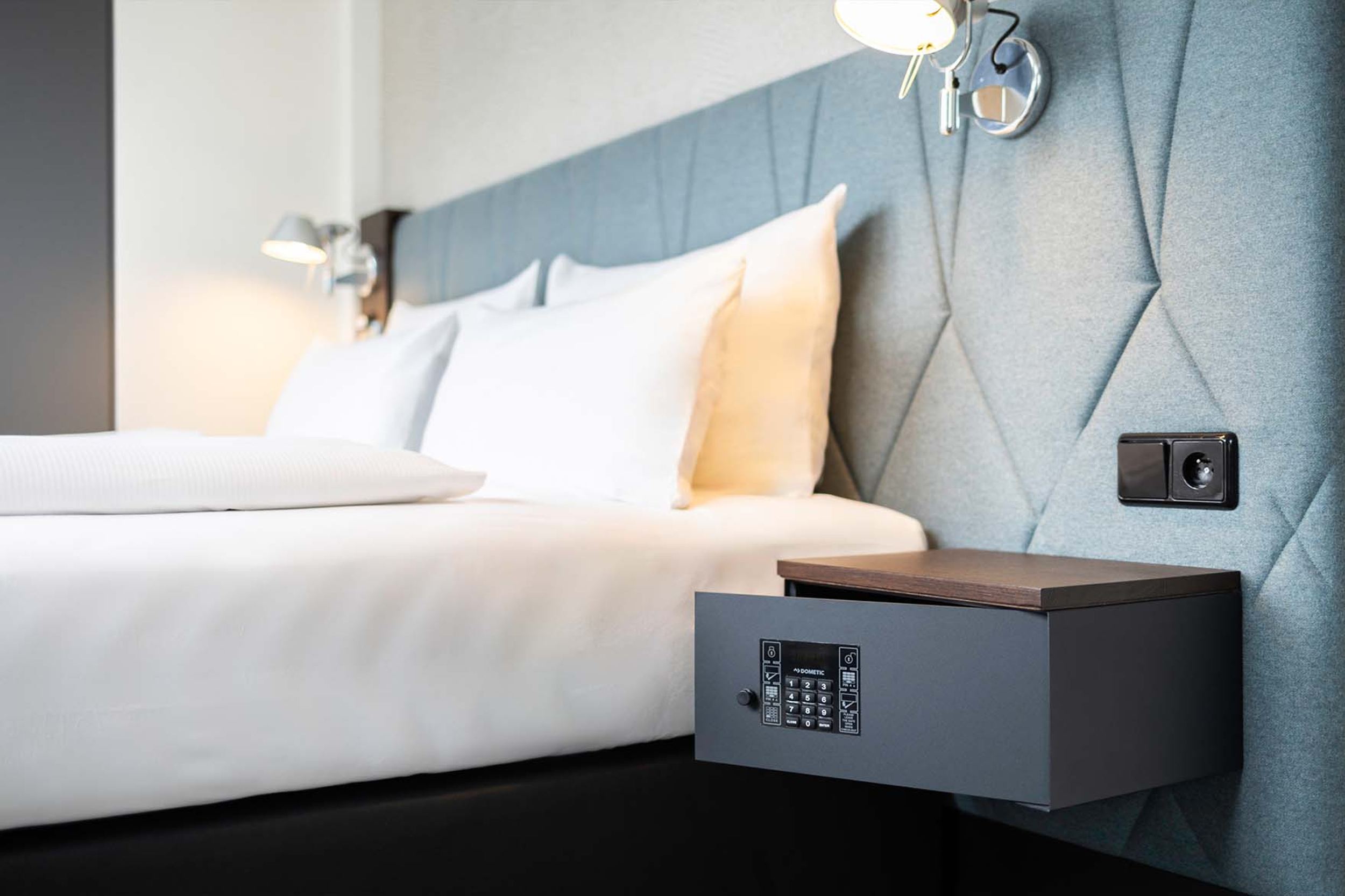 Hotel Brüssel Motel One seitlicher Blick auf ein Doppelbett sowie ein Nachttisch mit Safe