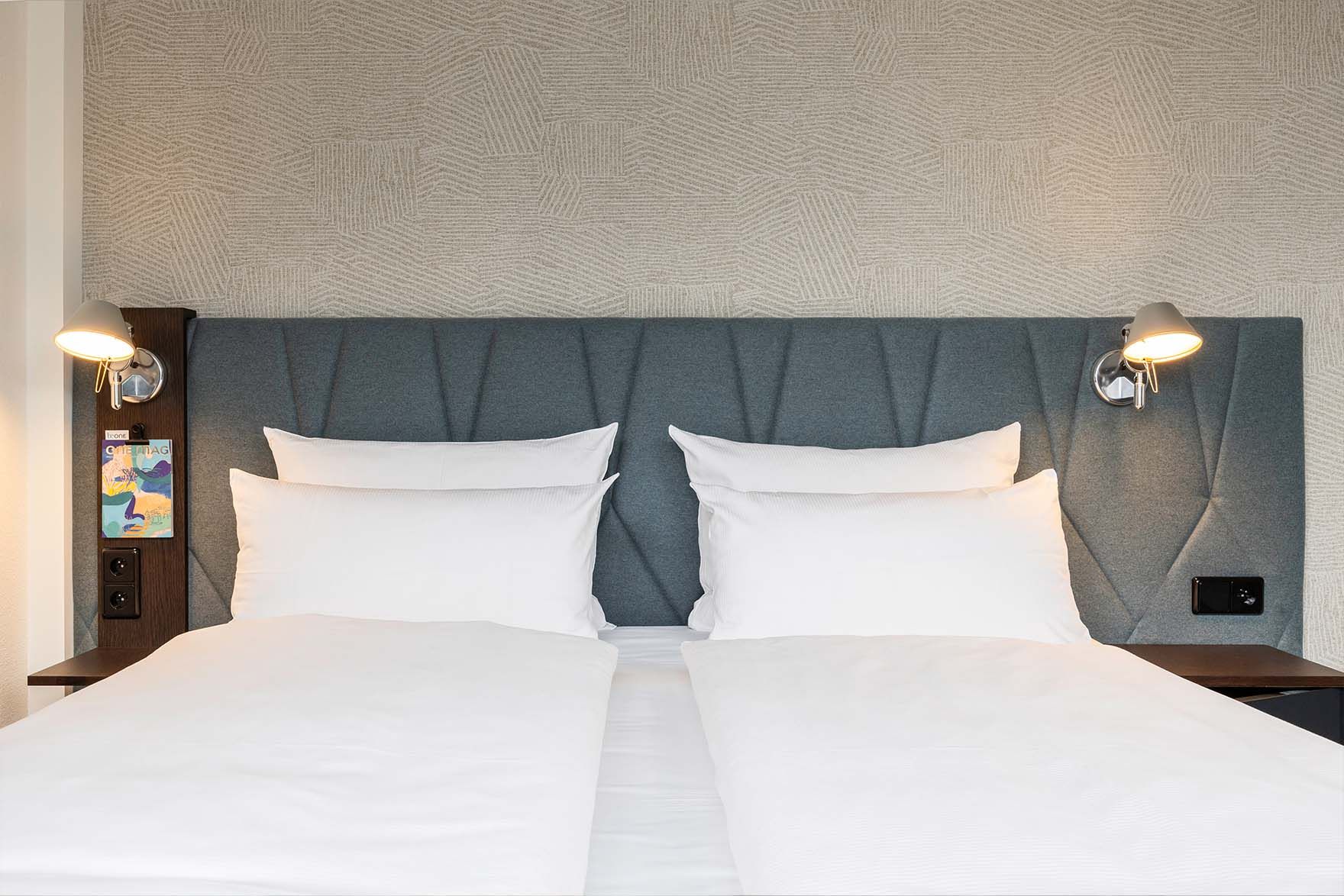 Designhotel Brüssel Motel One Blick auf ein komfortables Doppelbett mit weißer Bettwäsche