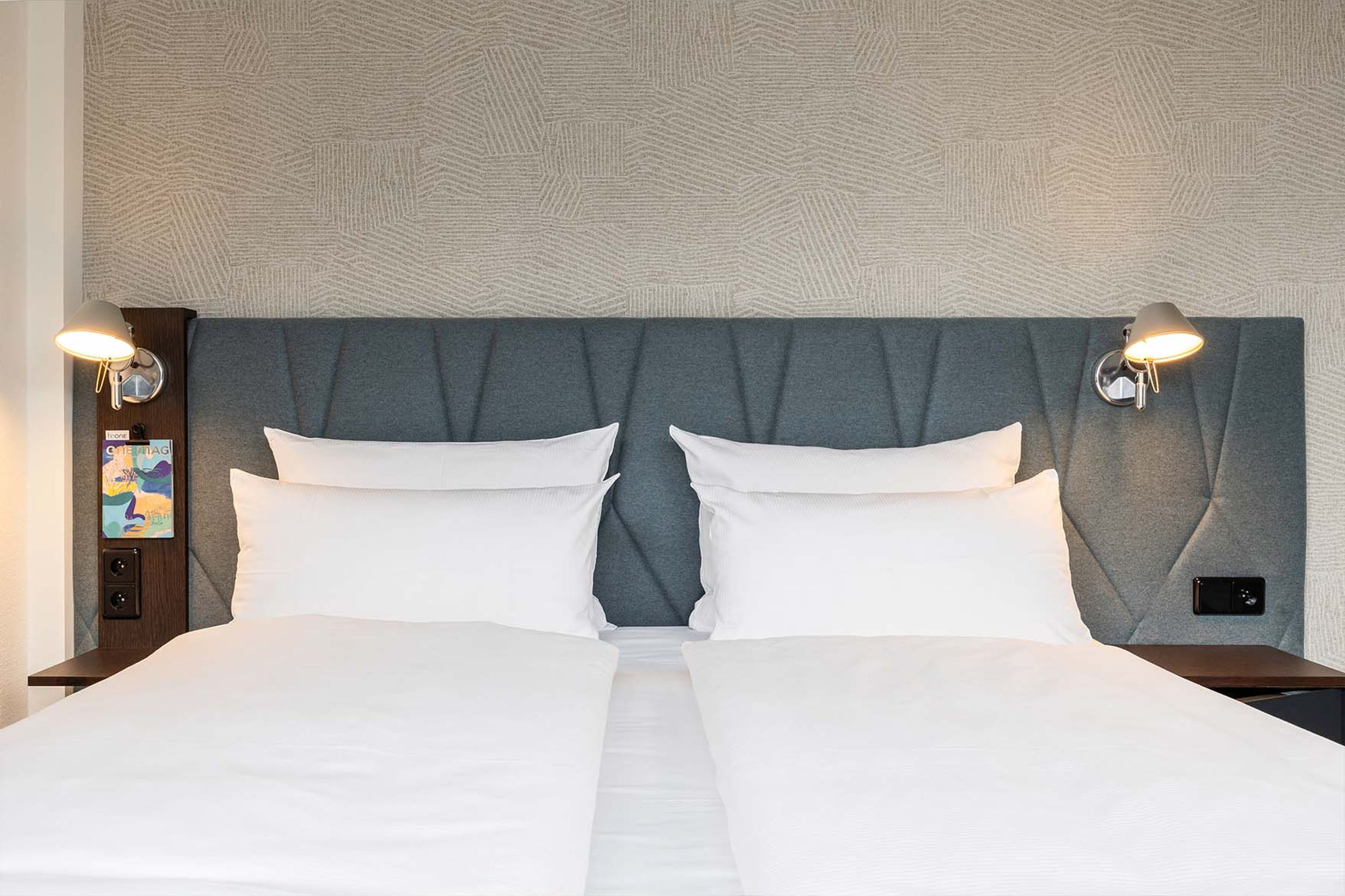 Designhotel Brüssel Motel One Blick auf ein komfortables Doppelbett mit weißer Bettwäsche