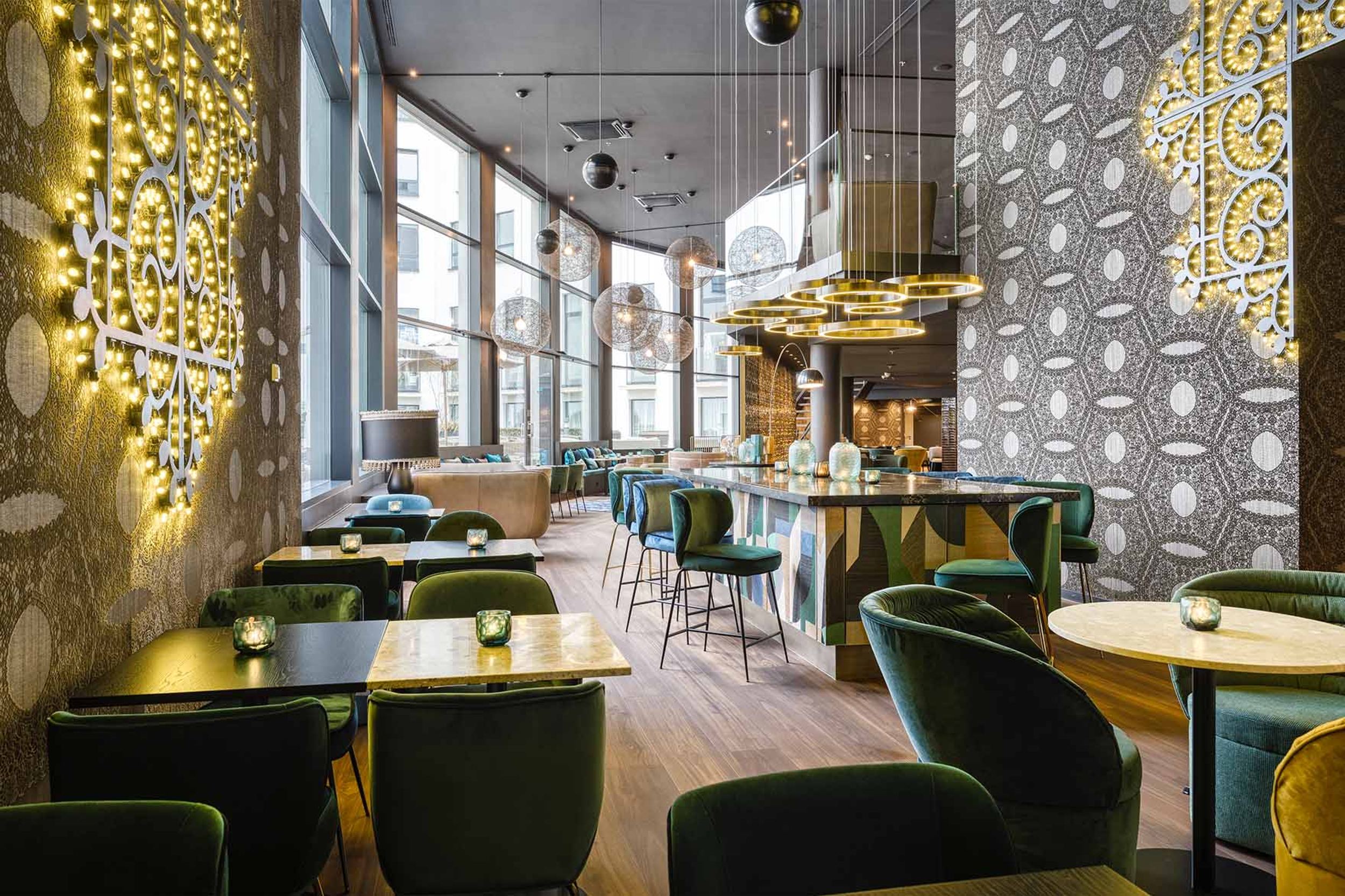 Designhotel Brüssel Motel One lichtdurchflutete Lounge mit bodentiefen Fenstern und zahlreichen Tischen und Stühlen zum Verweilen