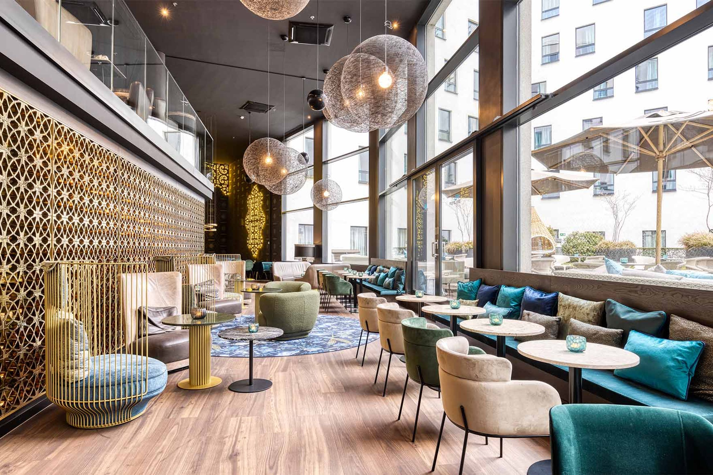 Hotel Brüssel Motel One lichtdurchflutete Lounge mit Sitzgelegenheiten und großer Fensterfront sowie Zugang zur Terrasse