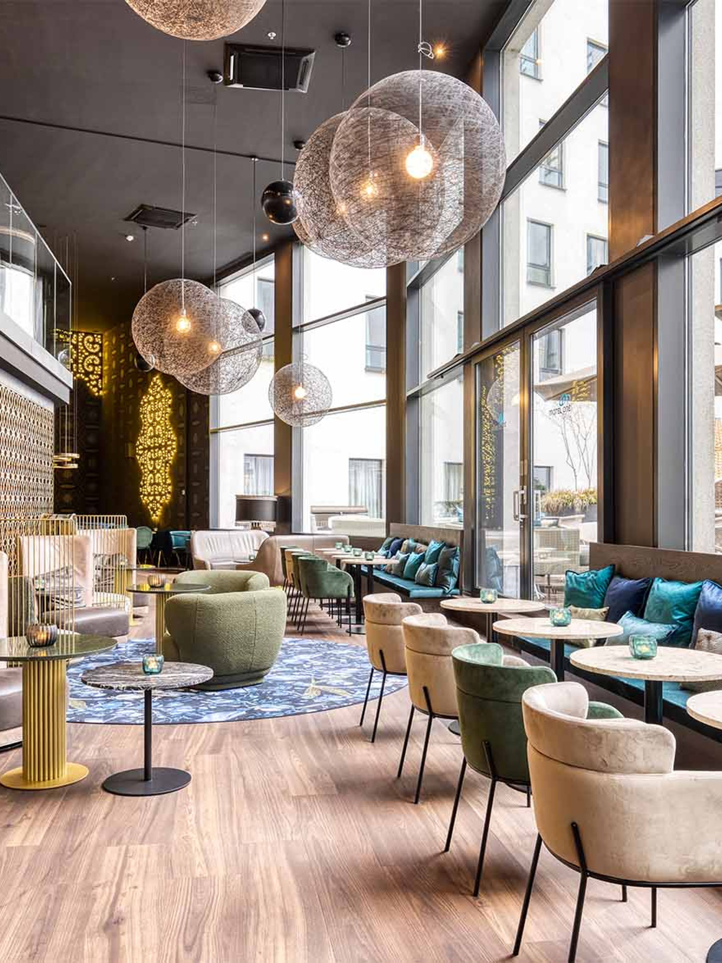 Hotel Brüssel Motel One lichtdurchflutete Lounge mit Sitzgelegenheiten und großer Fensterfront sowie Zugang zur Terrasse