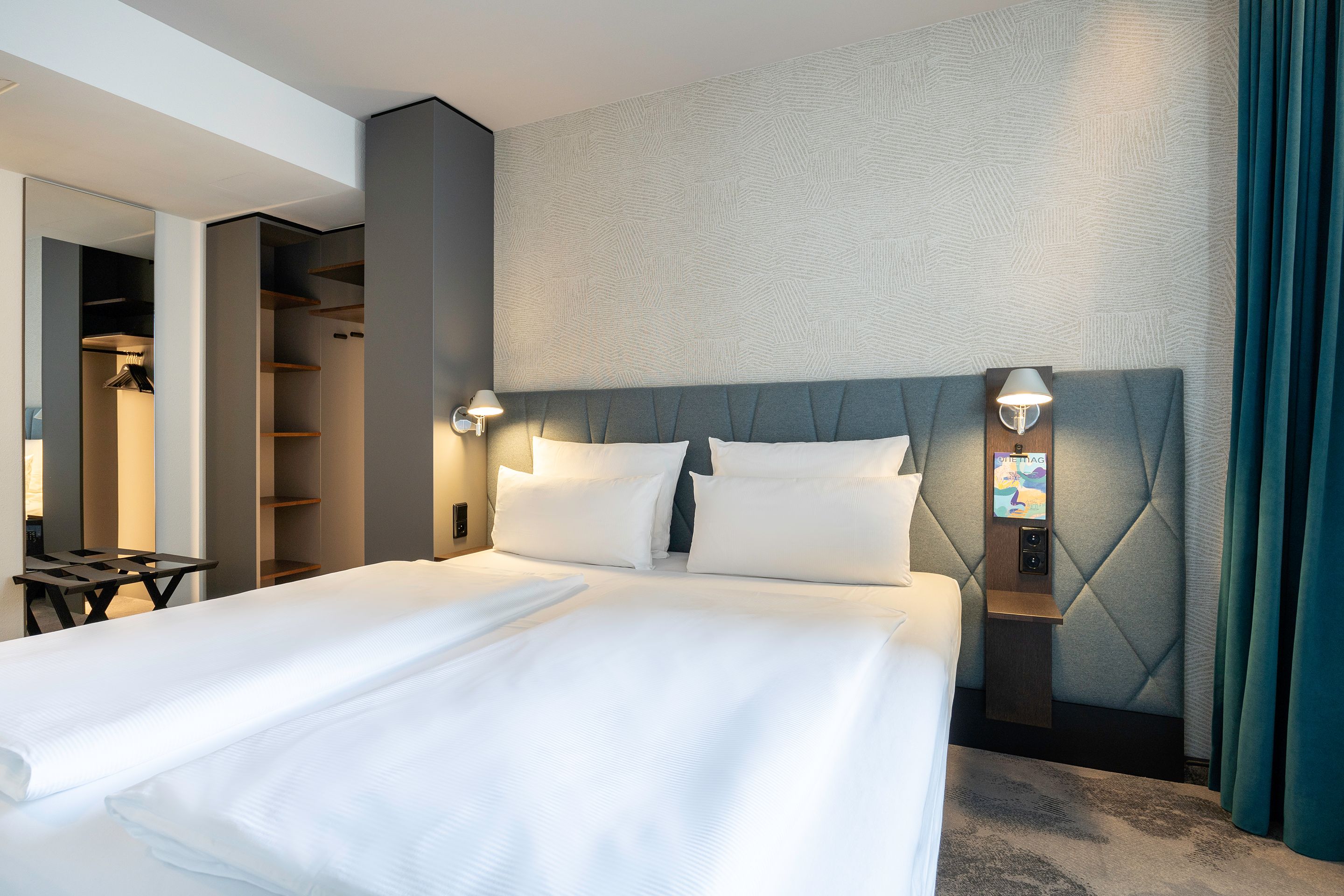 Hotel Brüssel Motel One lichtdurchflutetes Zimmer mit Doppelbett und offenem Schrank sowie bodentiefem Spiegel an der Wand