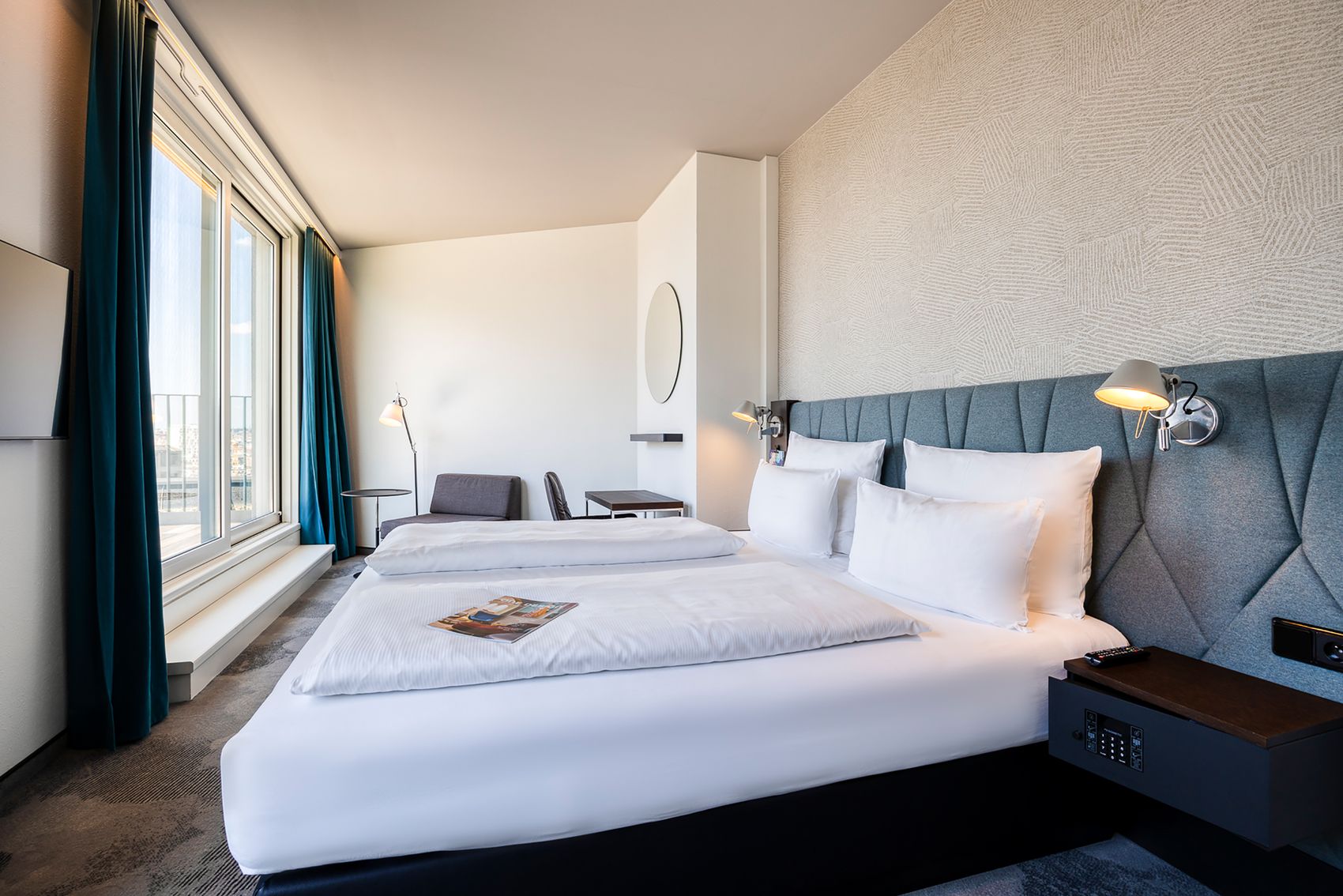 Designhotel Brüssel Motel One helles Zimmer mit großem Doppelbett sowie Balkonzugang