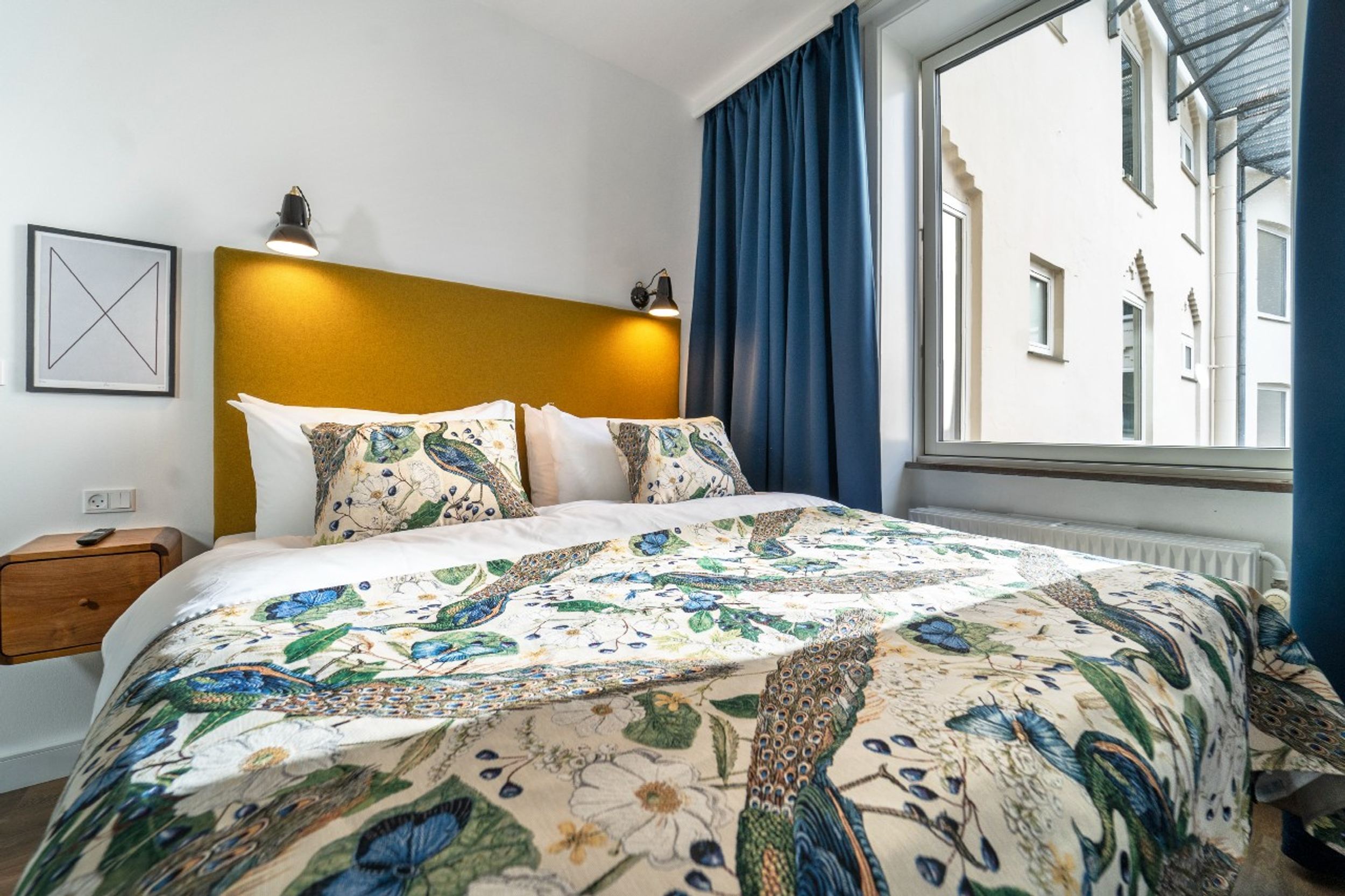 hotel Copenhagen Motel One room with comfortable bed next to large window with blue curtains