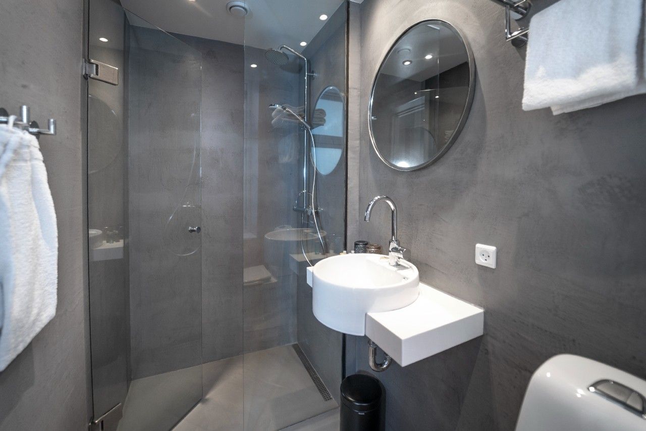 Hotel Kopenhagen Motel One Badezimmer mit großer Dusche sowie rundem Spiegel über weißem Waschbecken