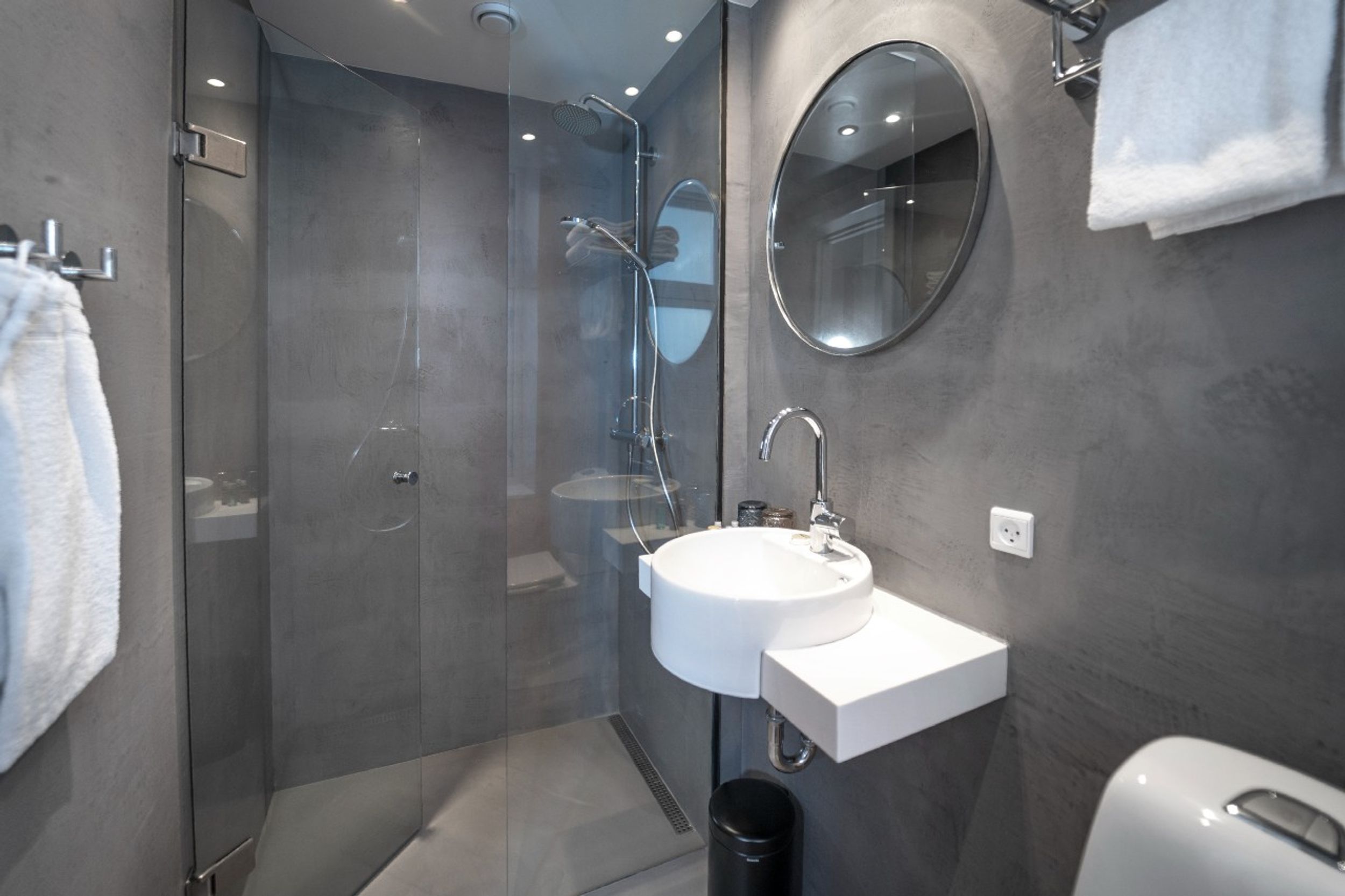 hotel Copenhagen Motel One bathroom with large shower and round mirror above white sink