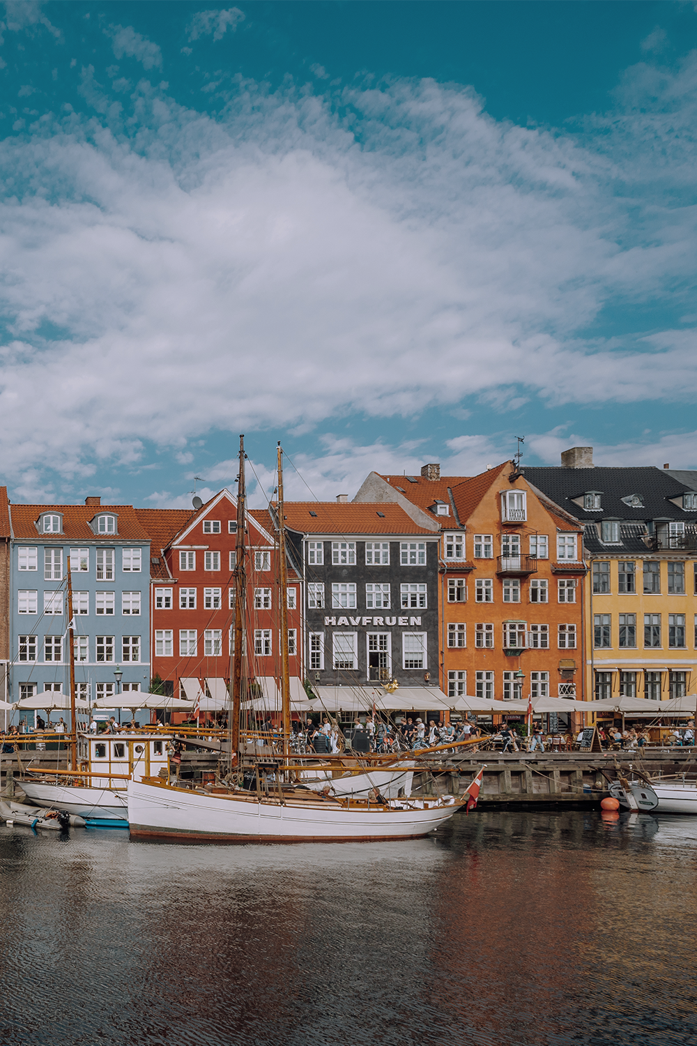Bunte historische Häuserzeile am Wasser mit kleinen Segelbooten im Vordergrund und einem bewölkten Himmel, typisch für einen lebendigen Hafenkai in einer europäischen Stadt. Bunte historische Häuserzeile am Wasser mit kleinen Segelbooten im Vordergrund und einem bewölkten Himmel, typisch für einen lebendigen Hafenkai in einer europäischen Stadt.