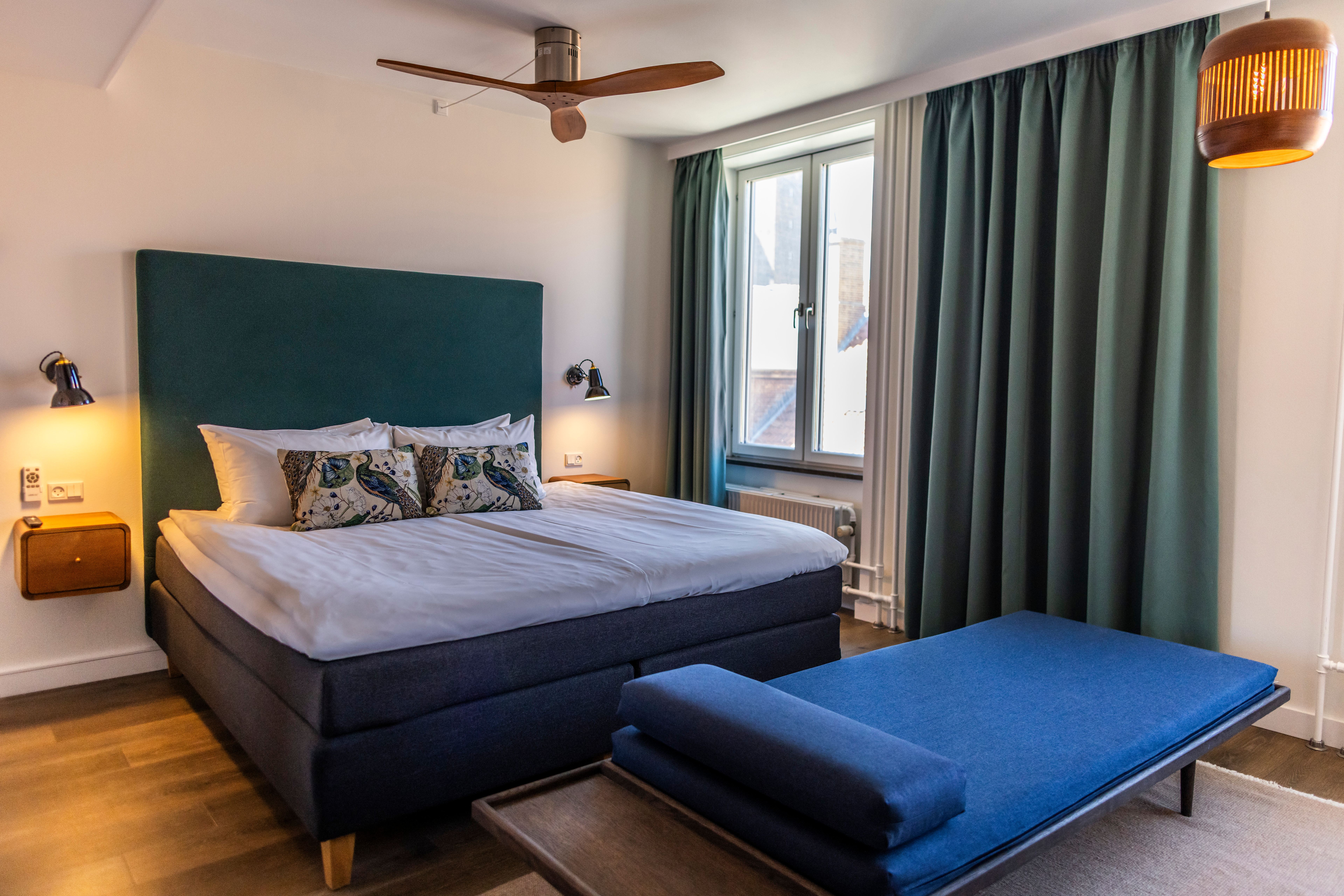 Hotel Motel One Copenhagen Modernes Hotelzimmer mit großem, komfortablem Doppelbett, weichen Kissen, großen Fenstern und ruhiger Atmosphäre durch gedämpfte Beleuchtung und dekorative Vorhänge. Hotel Motel One Copenhagen Modernes Hotelzimmer mit großem, komfortablem Doppelbett, weichen Kissen, großen Fenstern und ruhiger Atmosphäre durch gedämpfte Beleuchtung und dekorative Vorhänge.