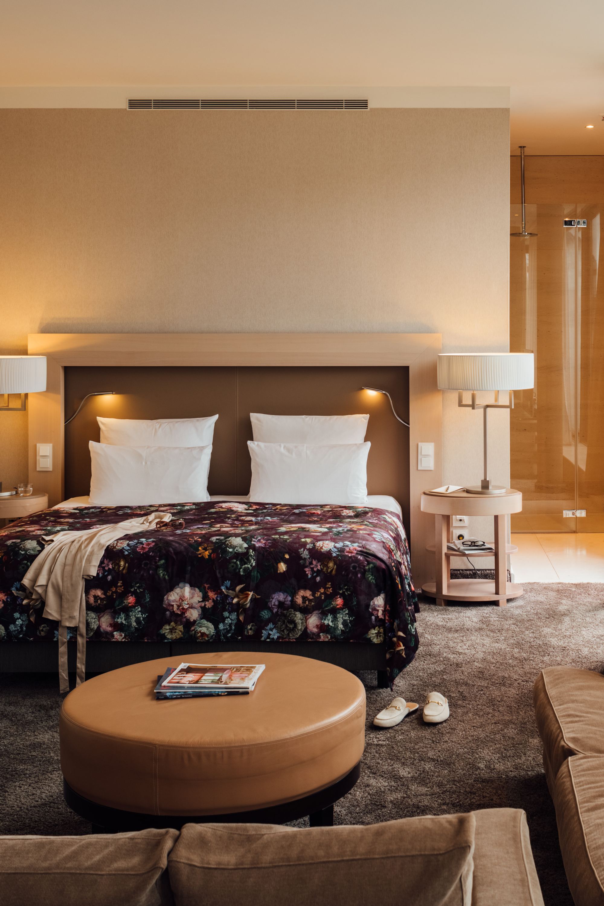 Modern eingerichtetes Hotelzimmer mit großem Doppelbett, gemütlichem Sofa, warmem Licht und Zugang zu einem Balkon mit Außenblick für entspannte Aufenthalte.
