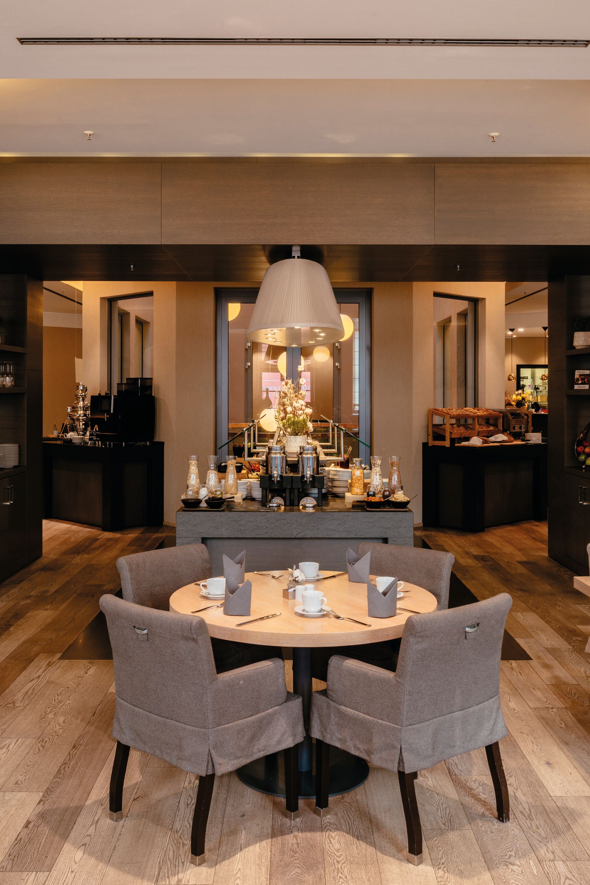 Modernes, stilvolles Restaurant mit warmem Licht, gemütlichen Sesseln und gedeckten Tischen, das eine einladende Atmosphäre für entspannte Mahlzeiten und geselliges Beisammensein bietet.