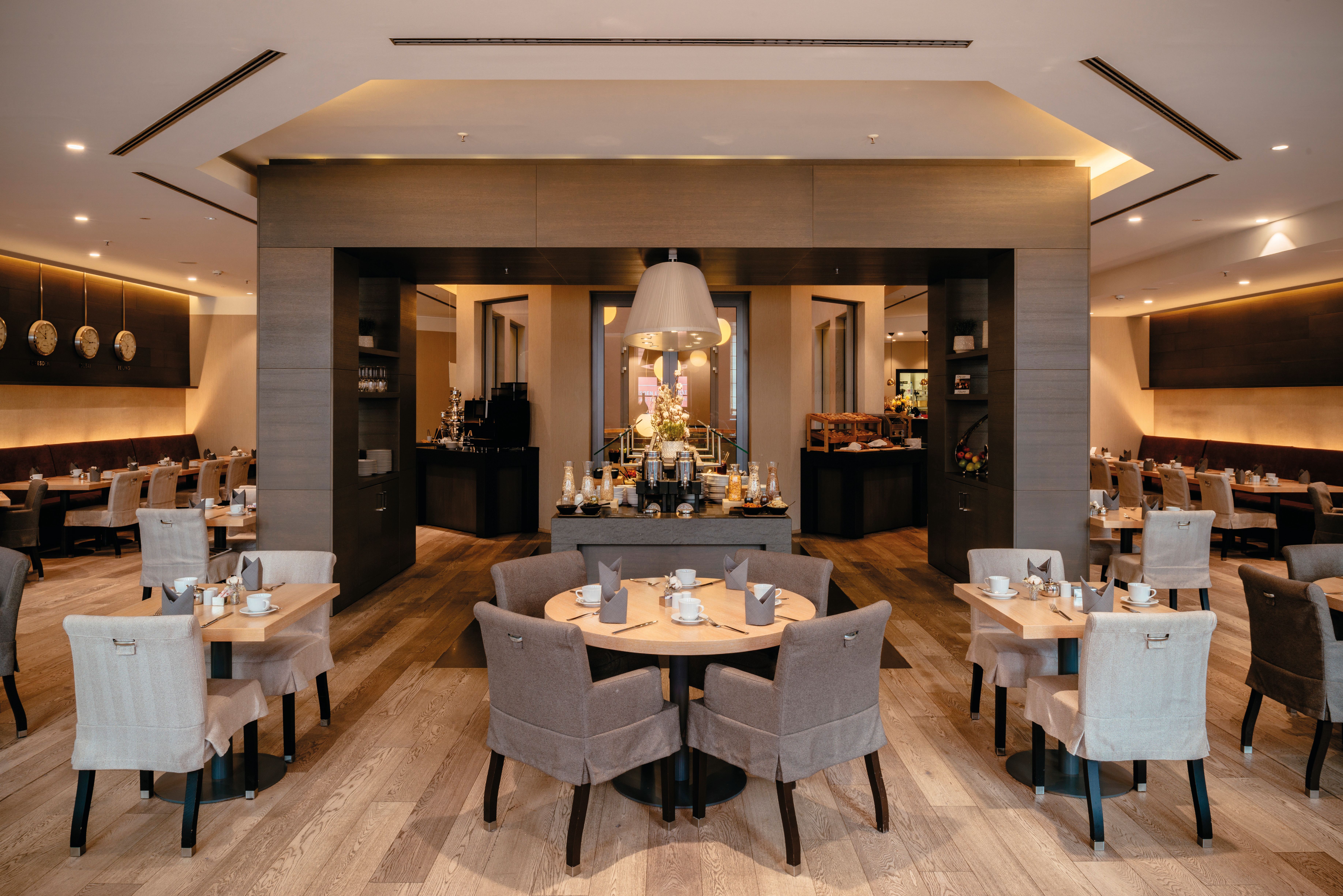 Modernes, stilvolles Restaurant mit warmem Licht, gemütlichen Sesseln und gedeckten Tischen, das eine einladende Atmosphäre für entspannte Mahlzeiten und geselliges Beisammensein bietet. Modernes, stilvolles Restaurant mit warmem Licht, gemütlichen Sesseln und gedeckten Tischen, das eine einladende Atmosphäre für entspannte Mahlzeiten und geselliges Beisammensein bietet.